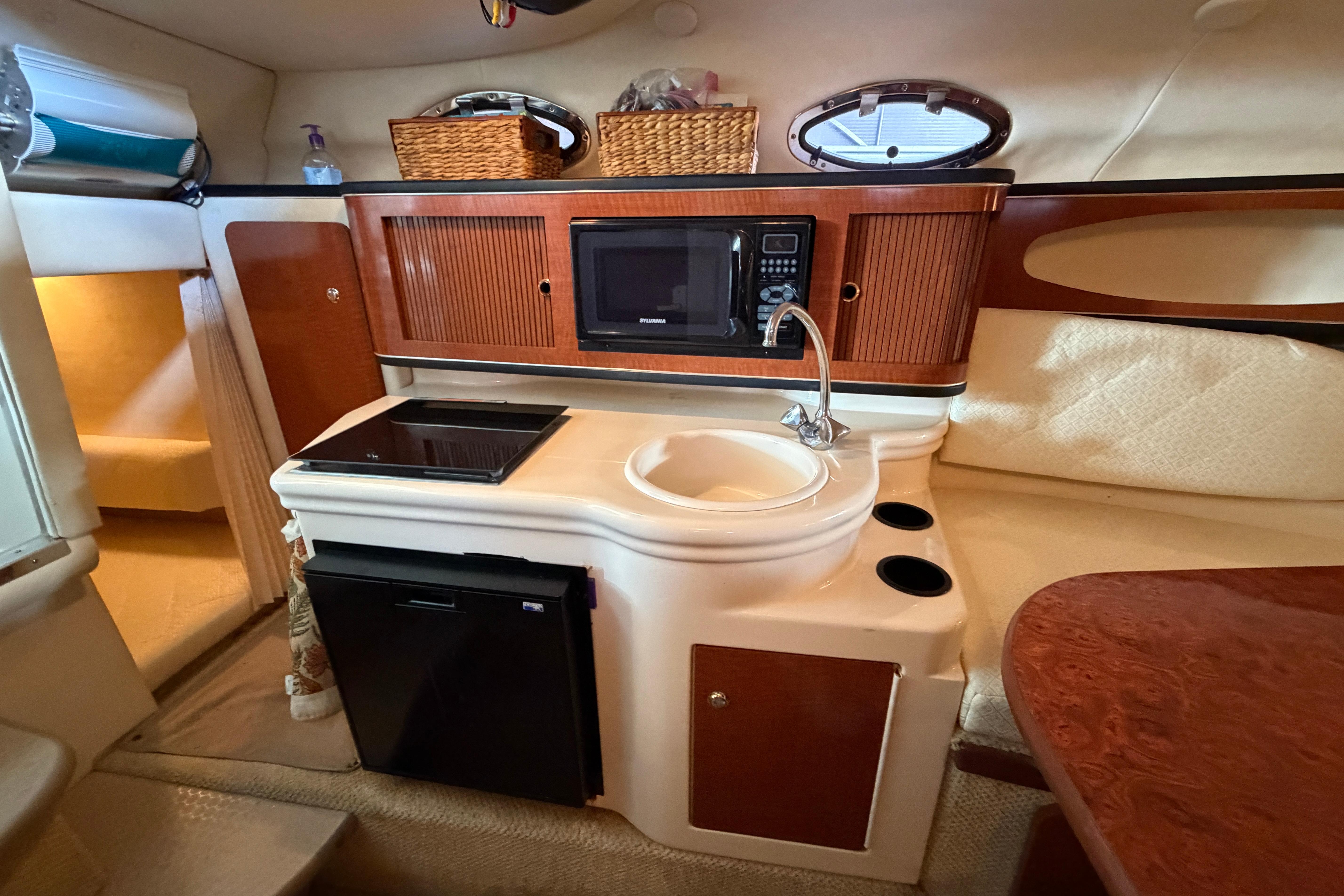 2004 Sea Ray Sundancer 260 cabin kitchen with microwave, sink, and compact fridge.
