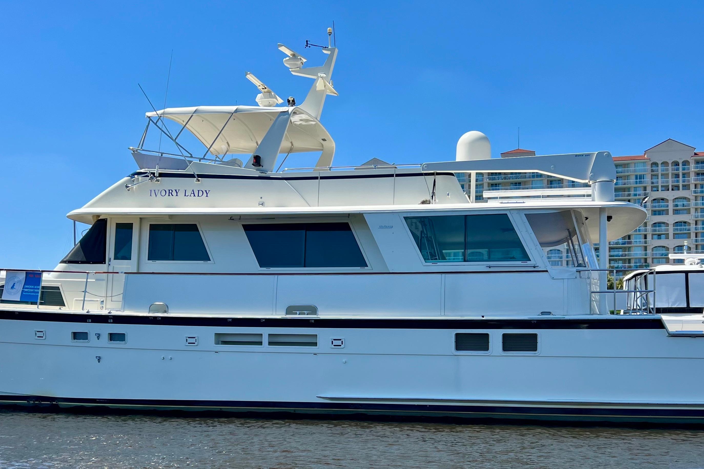 1987 Hatteras 70 Cockpit Motor Yacht docked, featuring sleek design and spacious upper deck.
