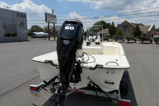 2025 Mako Pro Skiff 17 CC boat with 60 HP engine on trailer in parking lot.