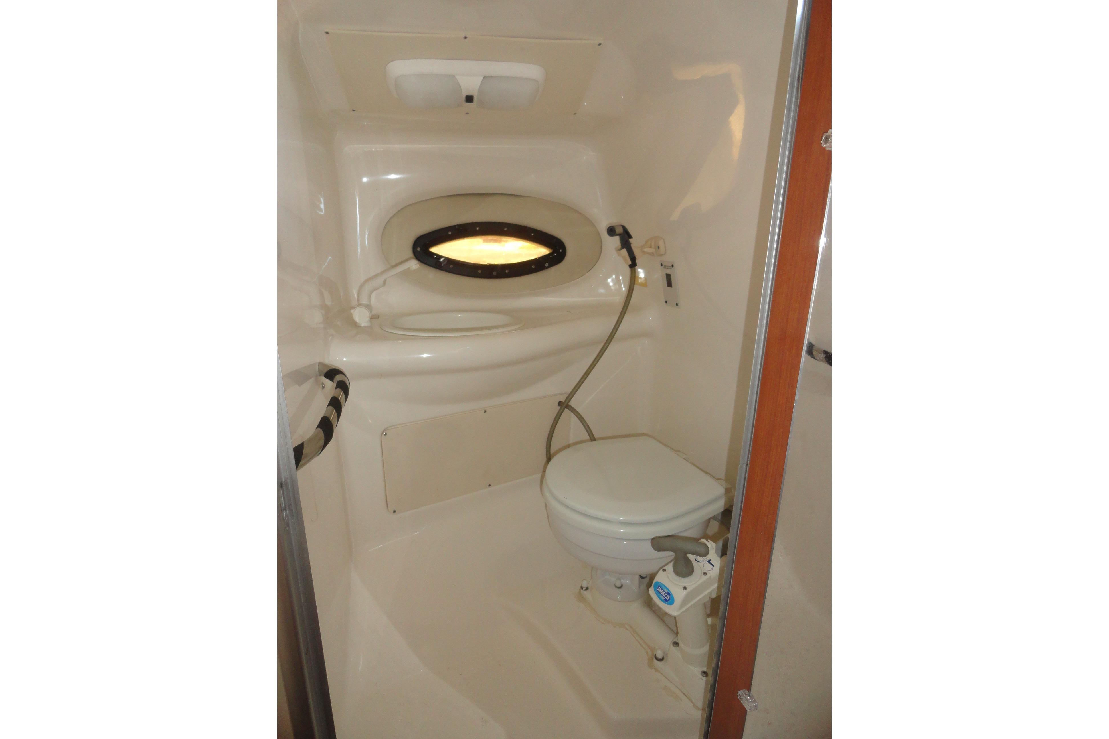 2001 Chaparral 265 SSi boat bathroom with compact toilet and porthole window.