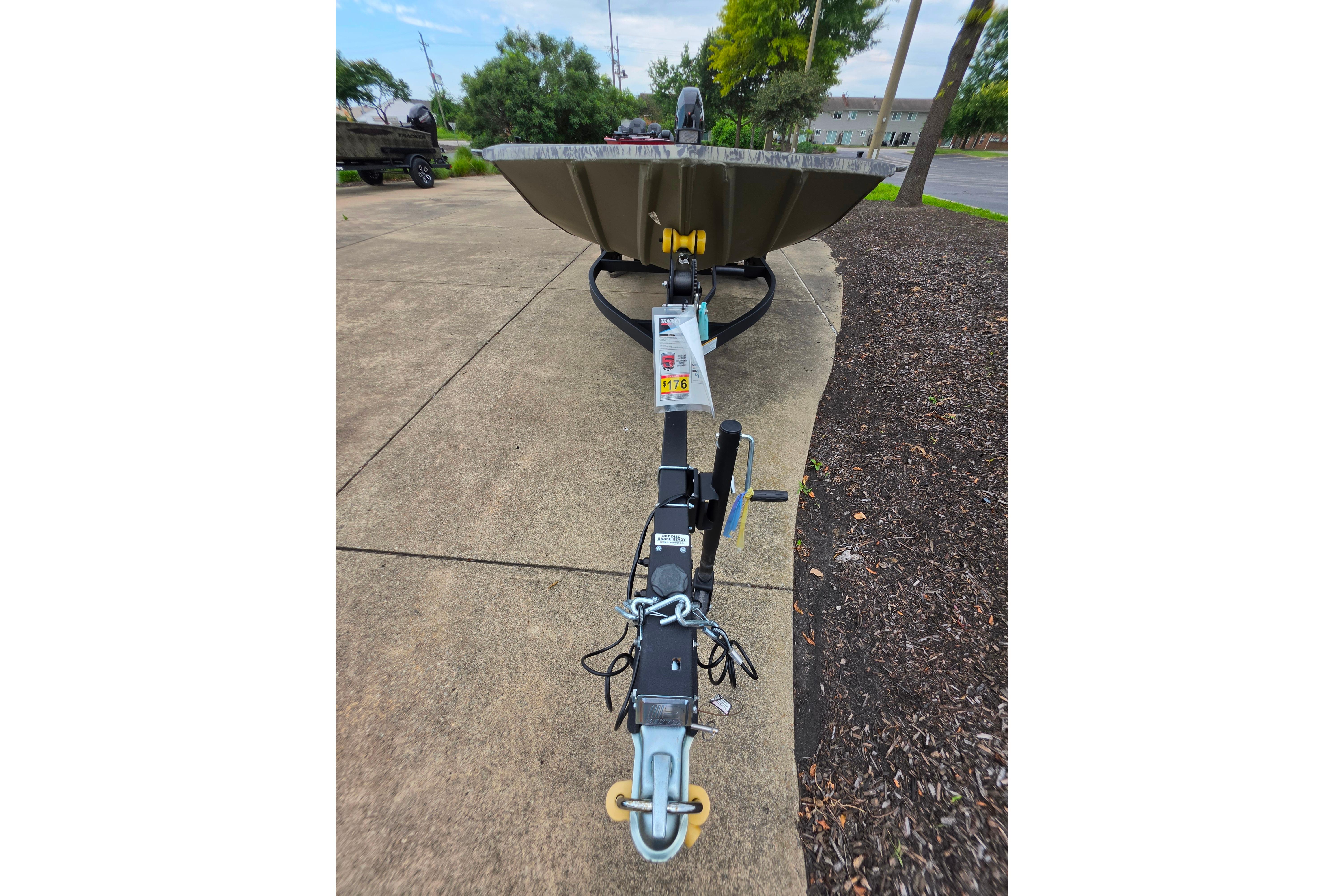 2026 Tracker Grizzly 1654 T Sportsman boat on trailer, parked on concrete.
