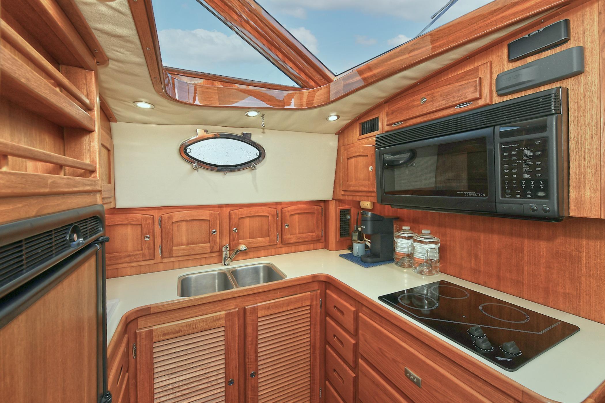 Luxurious 2005 San Juan Downeast Express yacht kitchen with wood cabinetry and modern appliances.