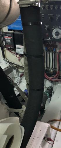 Engine room of a 1997 Bertram Convertible boat with visible wiring and hoses.