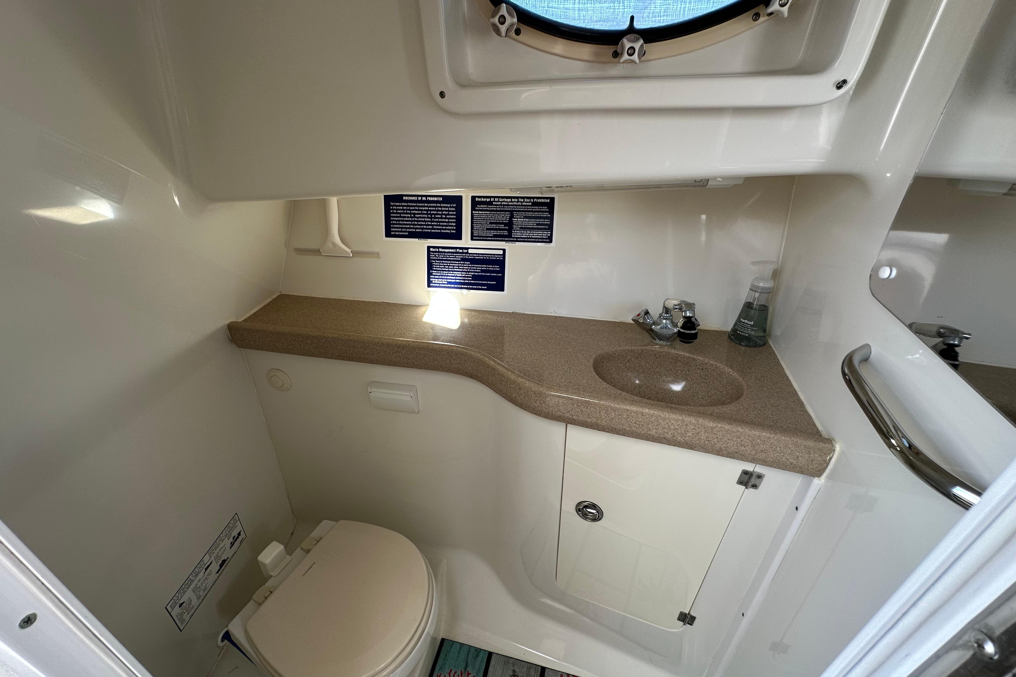 2006 Pro-Line 32 Express boat bathroom with sink, toilet, and storage cabinet.