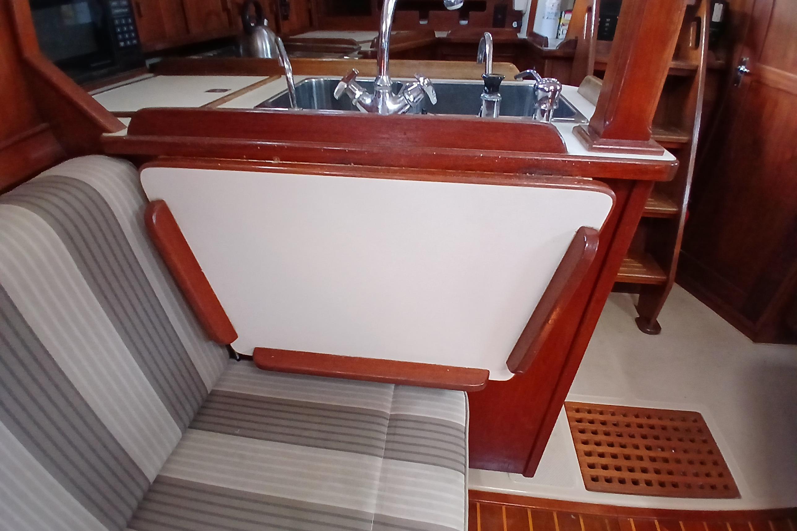 Interior of 1995 Island Packet 37 sailboat with wooden cabinetry and striped seating.