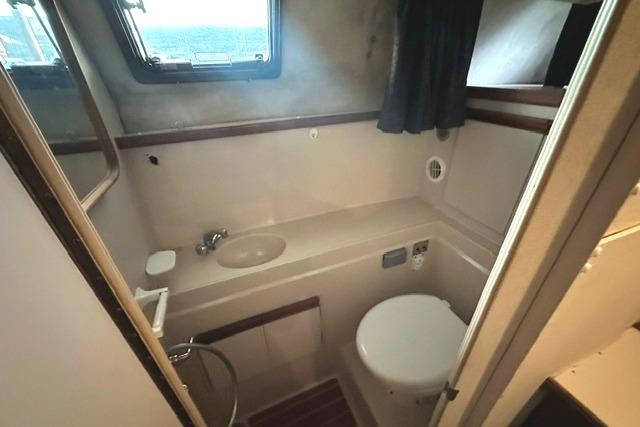1989 Carver 32 Aft Cabin Motor Yacht bathroom with sink, toilet, and window.