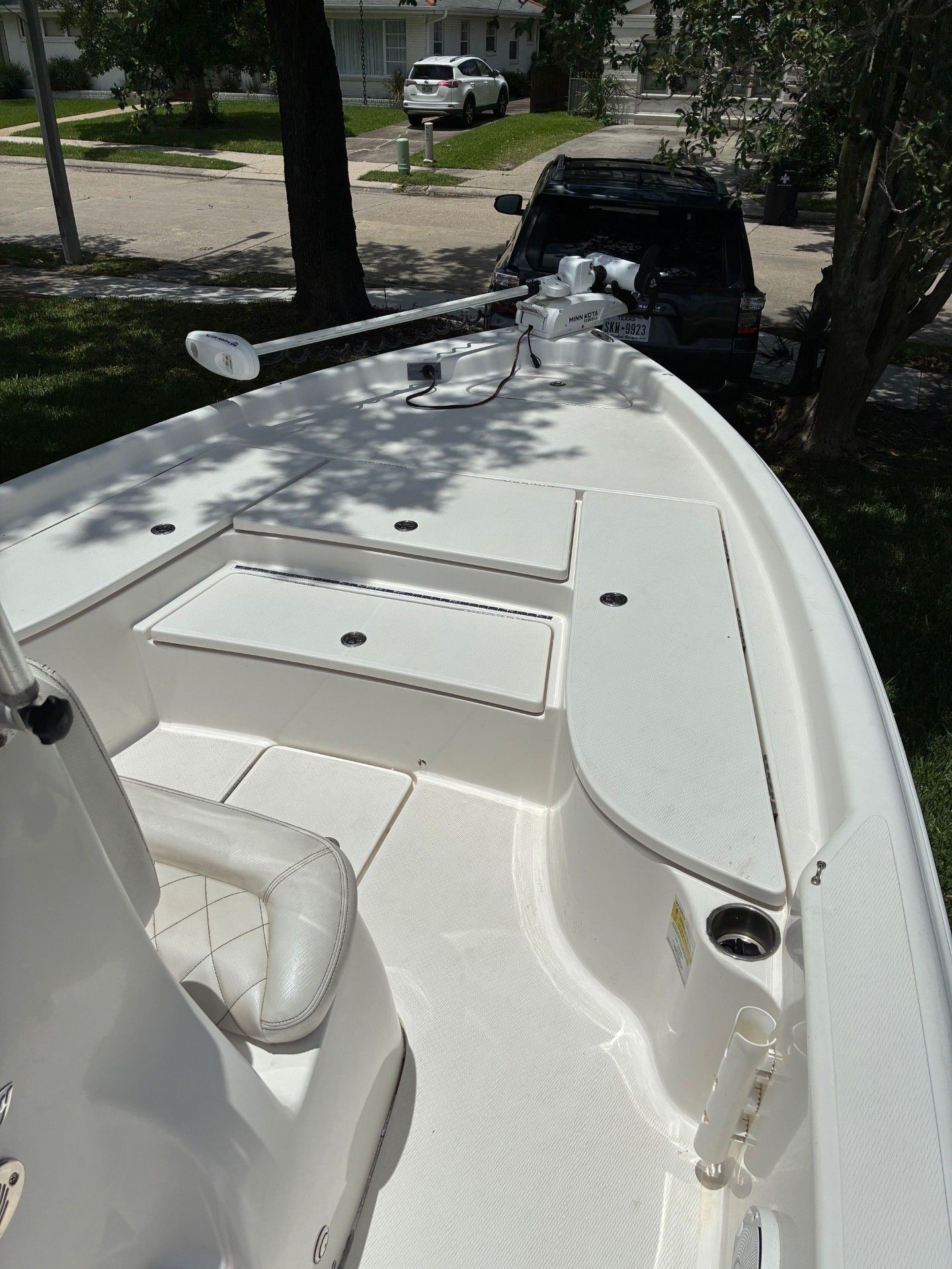 The boat features a spacious deck with storage and is parked on a trailer.