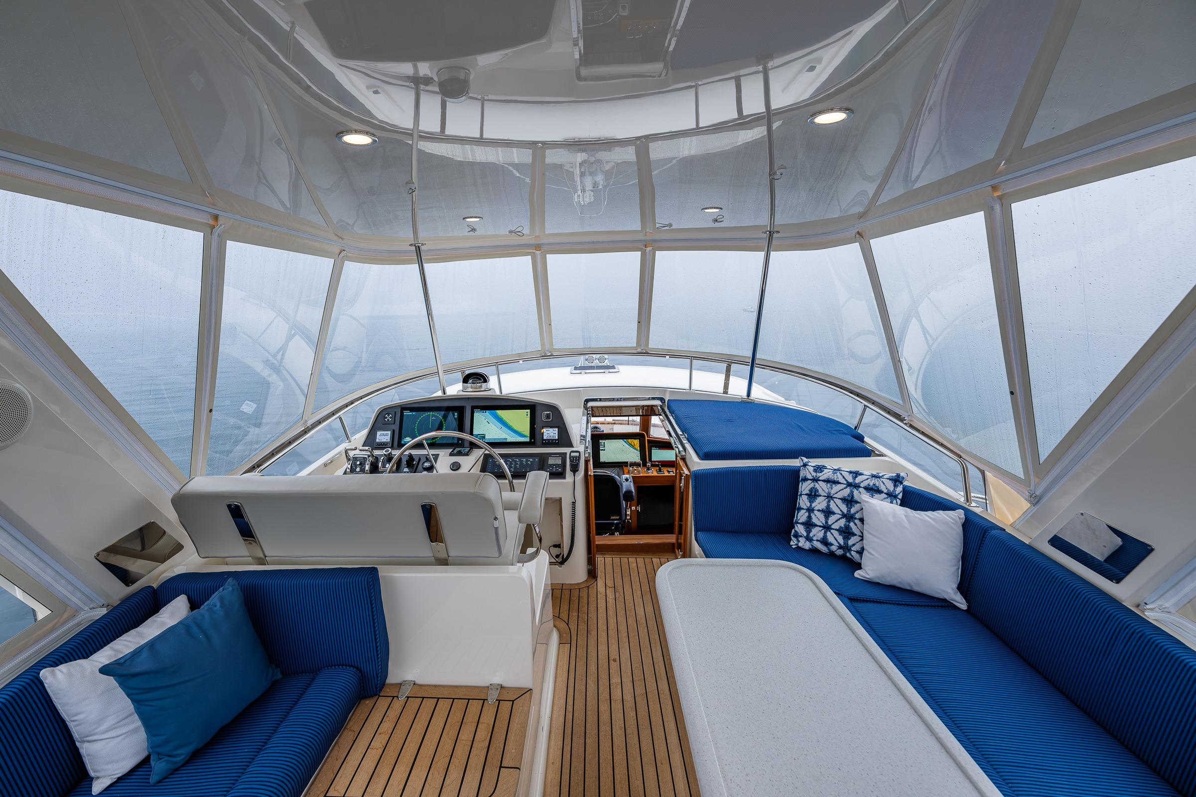 Luxurious 2026 Fleming 55 Pilothouse interior with blue seating and modern navigation equipment.