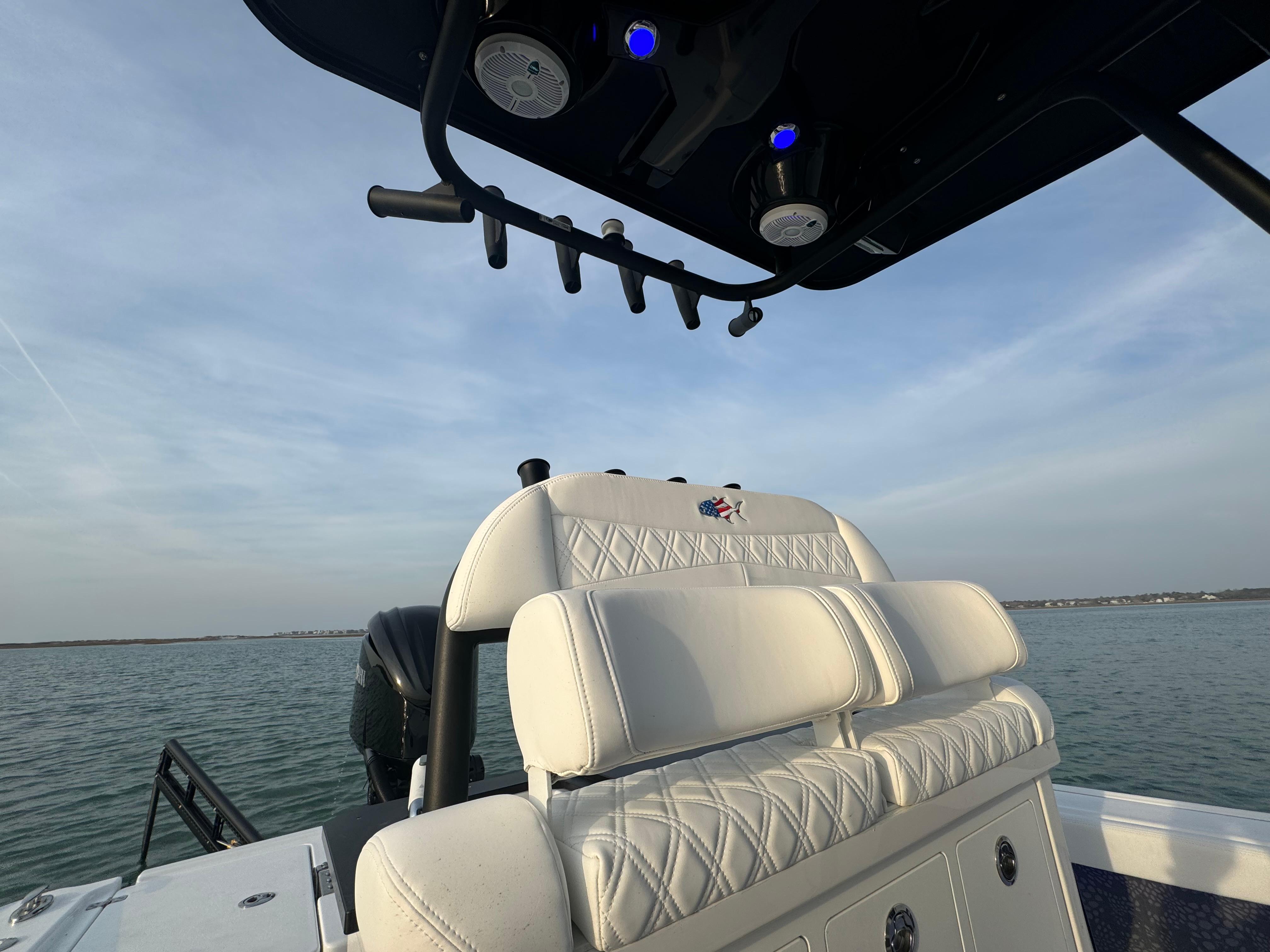 2025 Crevalle 24 HCO boat interior with white seating and rod holders, on calm water.