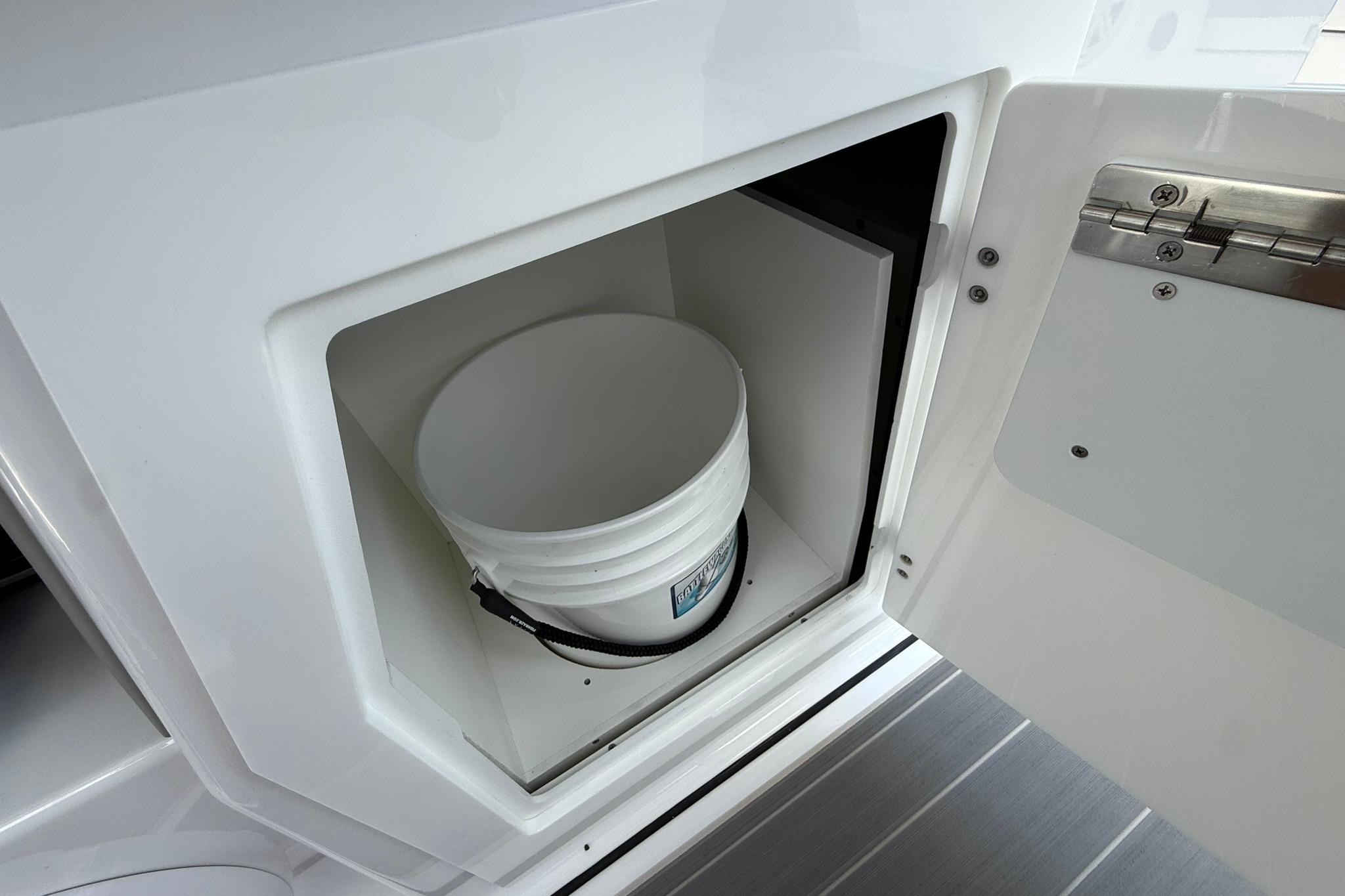 Storage compartment with a bucket inside the 2027 Monterey Elite 30 OB boat.