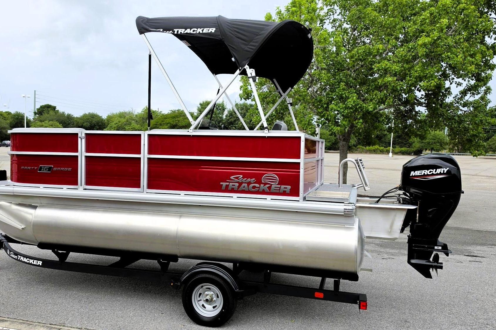 2026 Sun Tracker Party Barge 16 DLX pontoon boat with Mercury engine, parked outdoors.