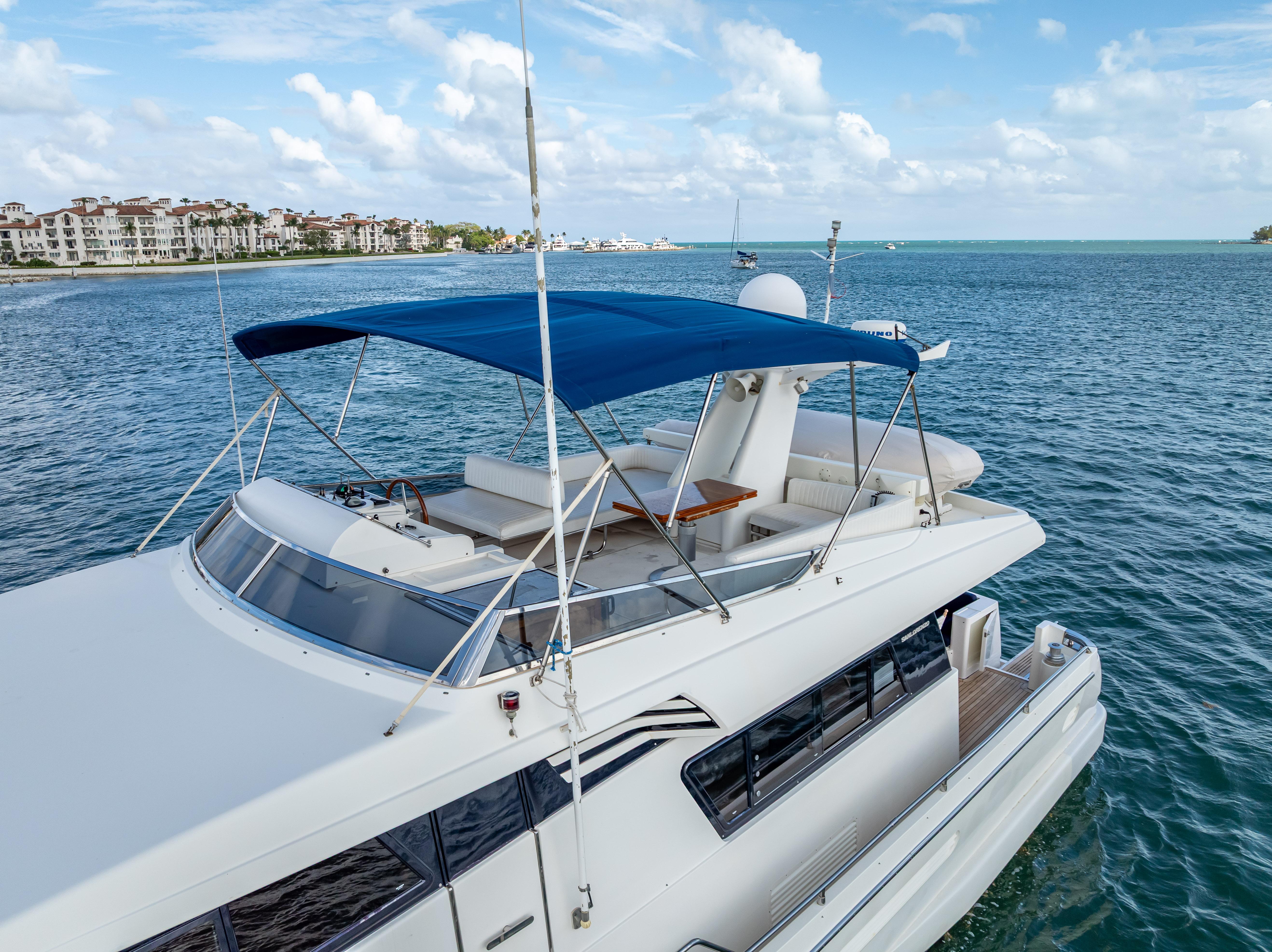 Sanlorenzo 62 yacht, 1995 model, cruising on a sunny day with blue canopy.