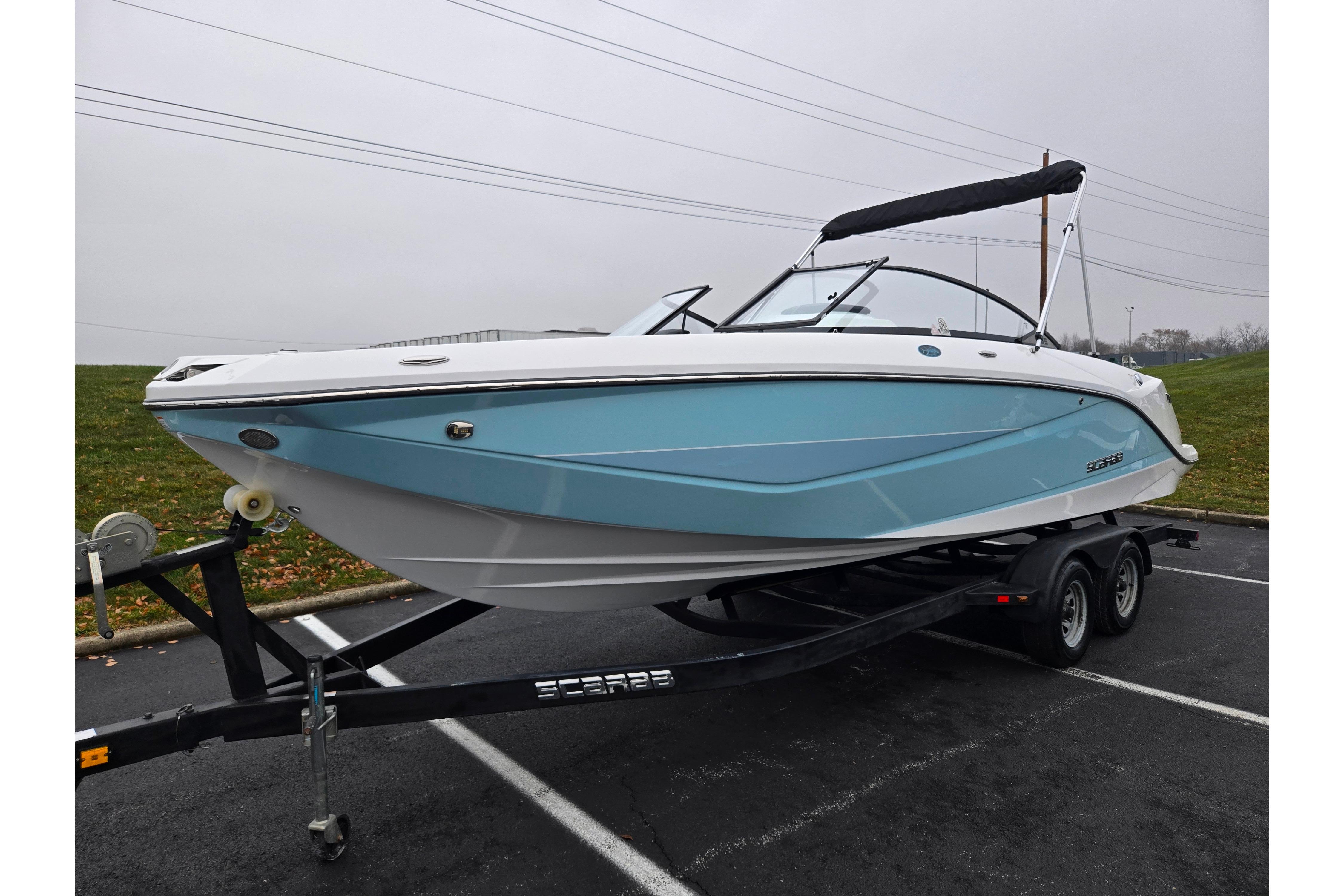 2021 Scarab 255 ID boat on trailer, blue and white design, parked outdoors.