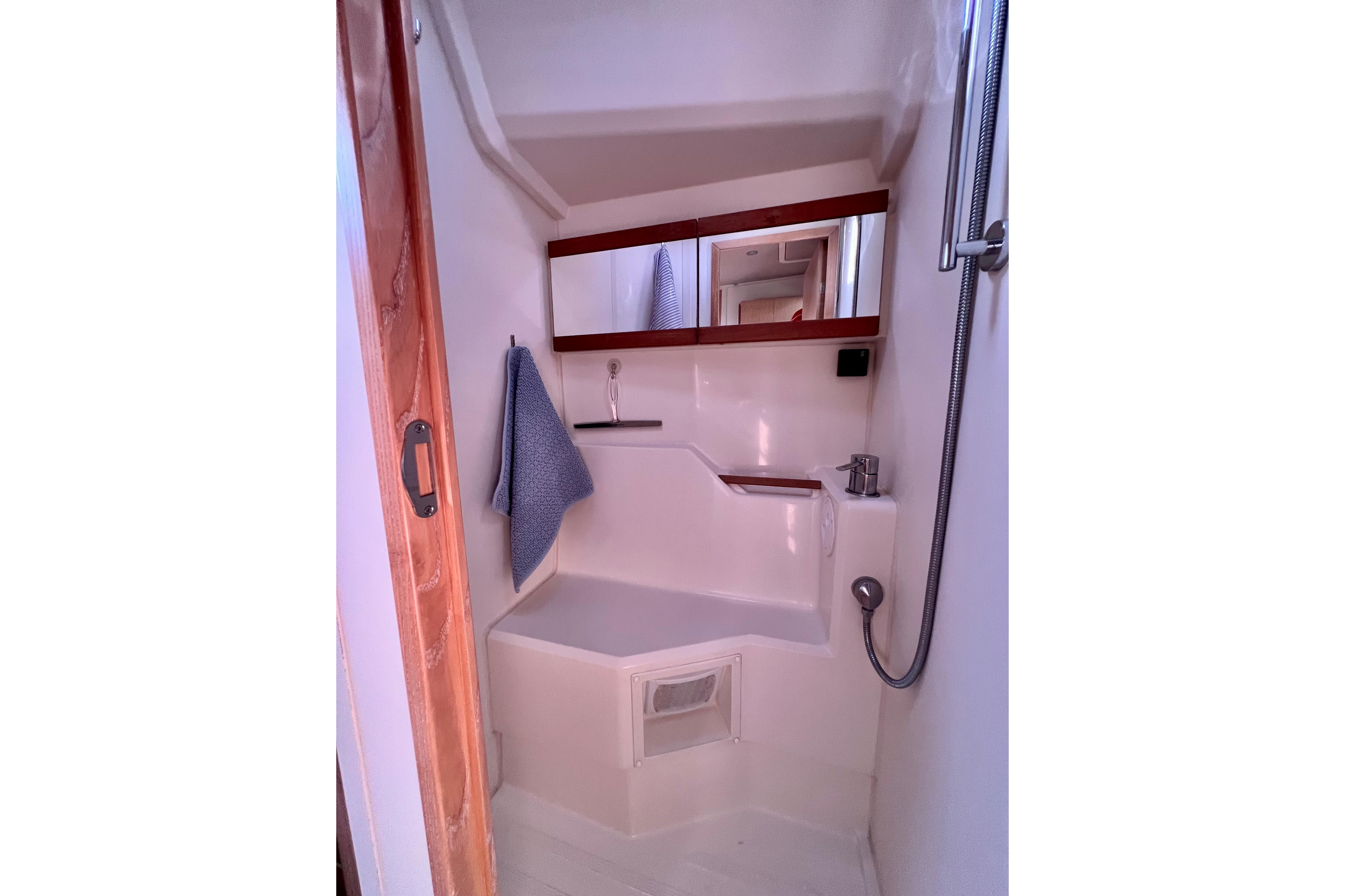 Compact bathroom in a 2016 Hanse 455 yacht, featuring a shower and mirror.