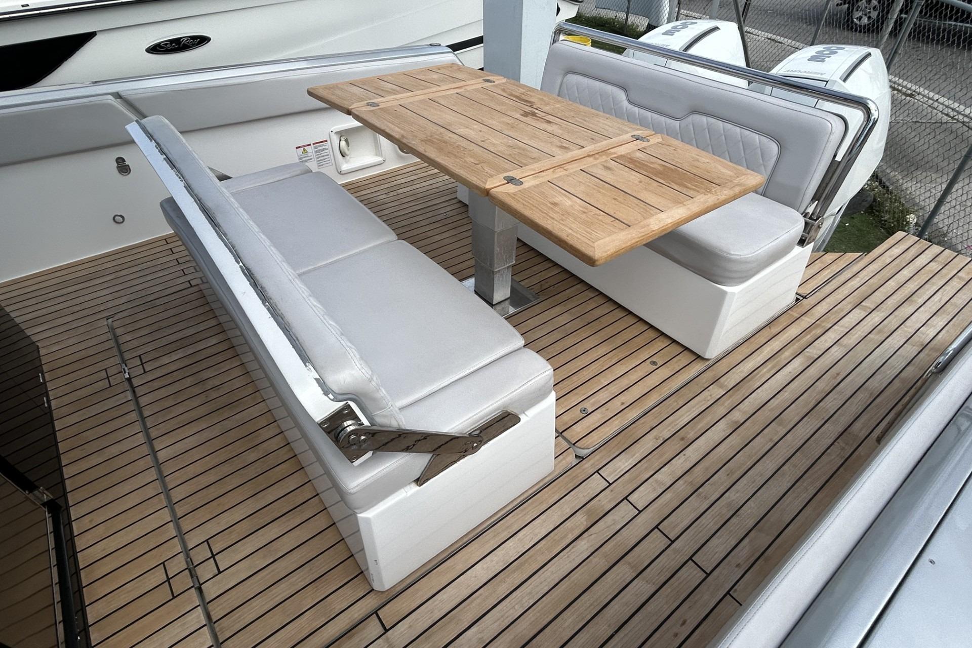 2023 Schaefer V33 boat interior with wooden table and cushioned seating on deck.