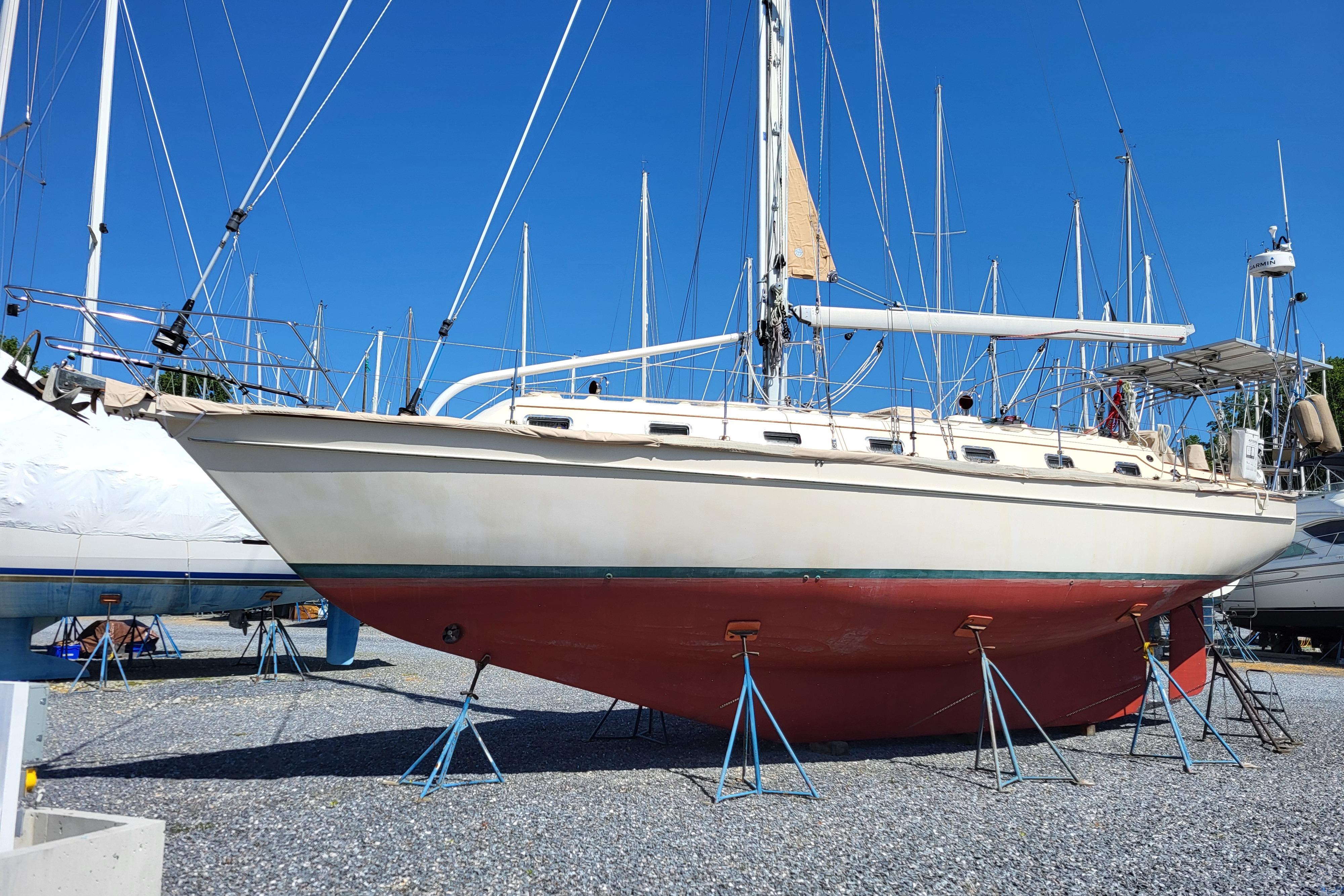 Island Packet 420 sailboat from 2000 on stands in a boatyard under clear blue sky.