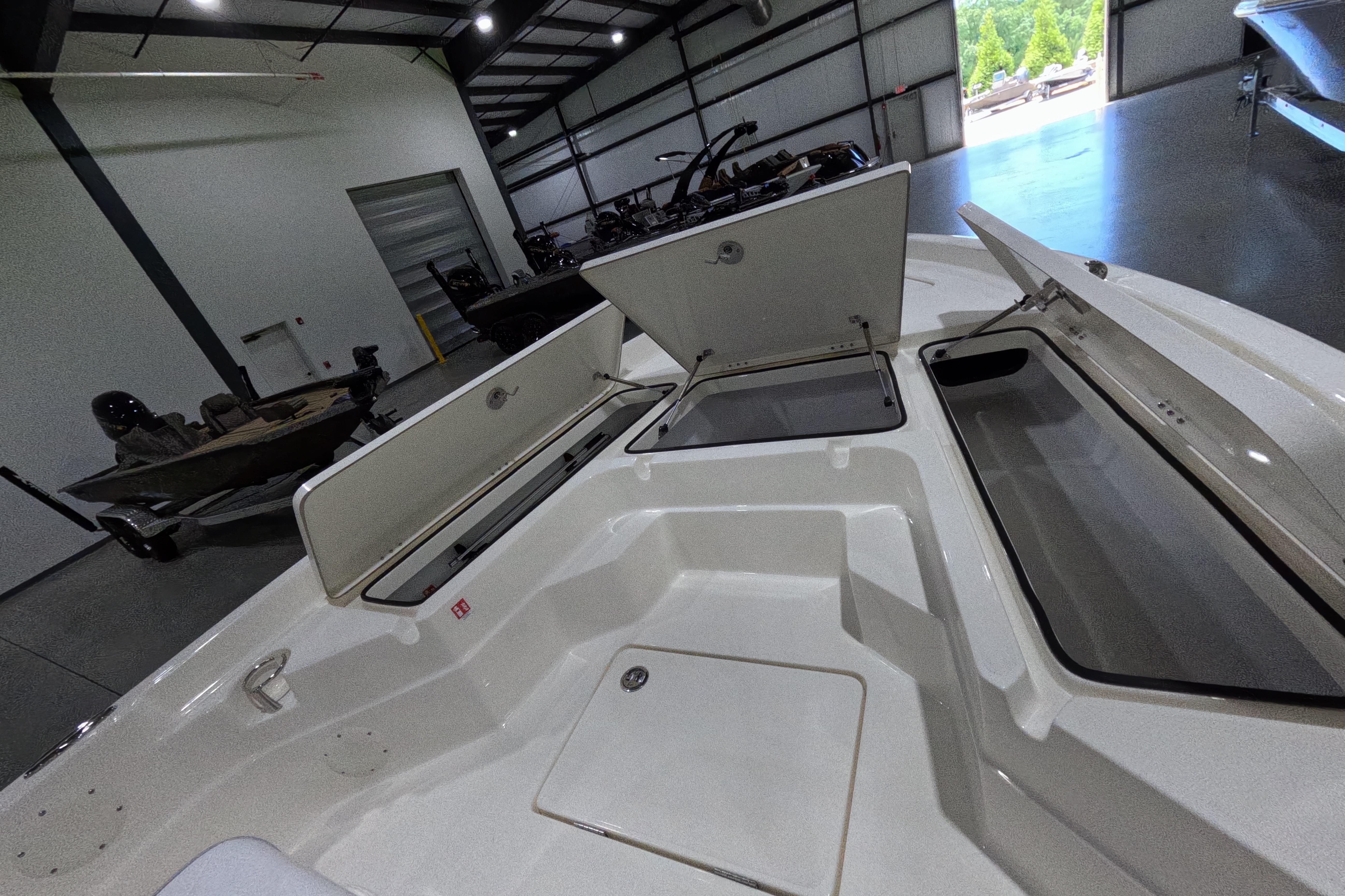 2026 Skeeter SX230 boat interior with open storage compartments in a showroom.