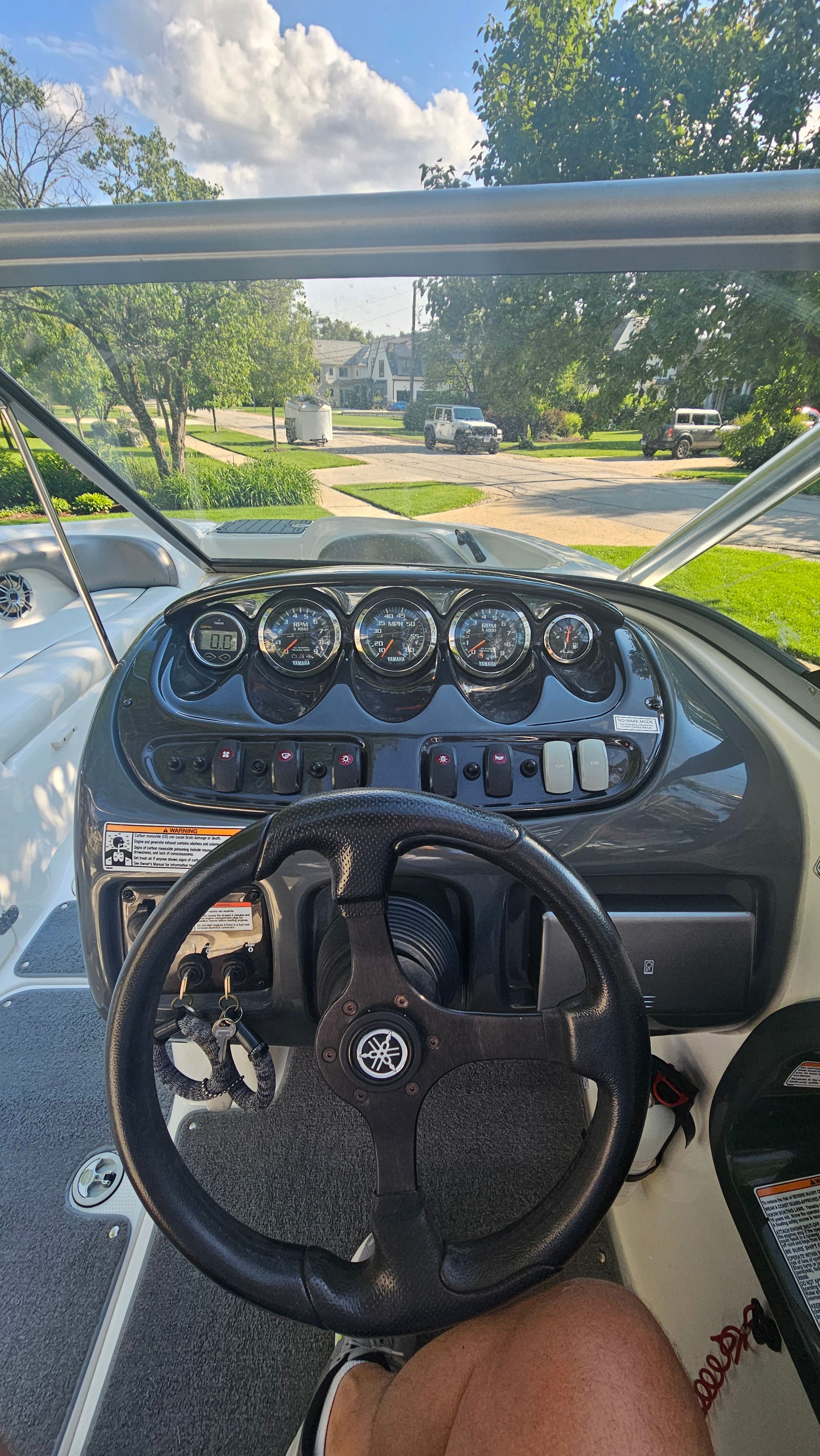 The image shows the cockpit of a 2010 Yamaha AR210 boat with a black steering wheel.