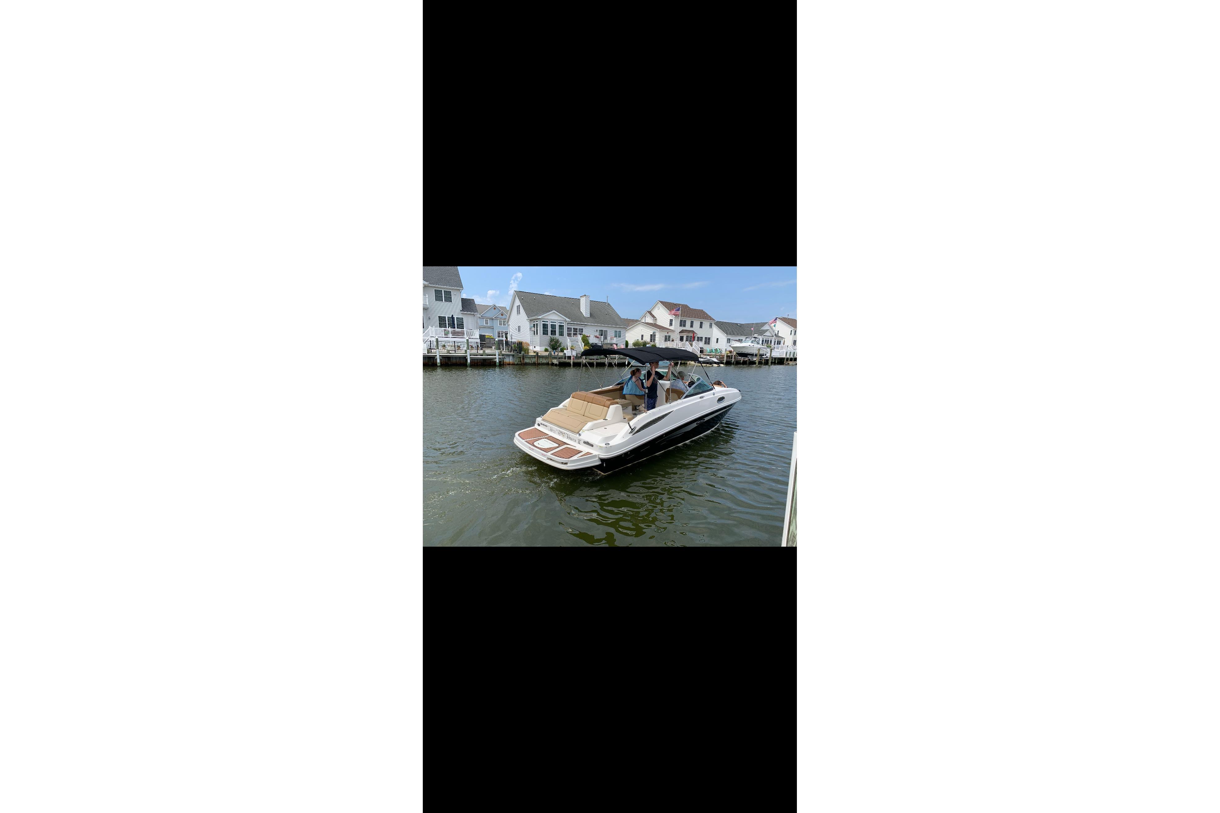 2014 Sea Ray 260 Sundeck boat cruising near waterfront homes.