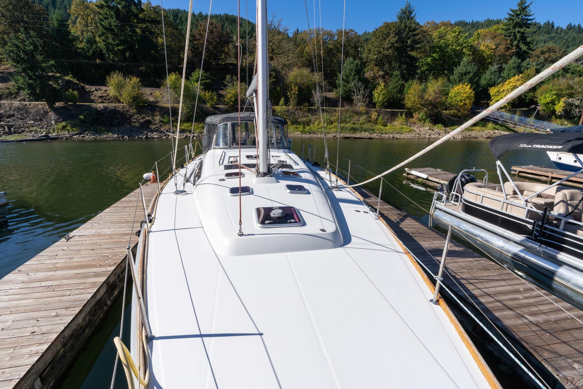 2013 Beneteau Oceanis 50 sailboat docked on a serene lake with lush greenery.