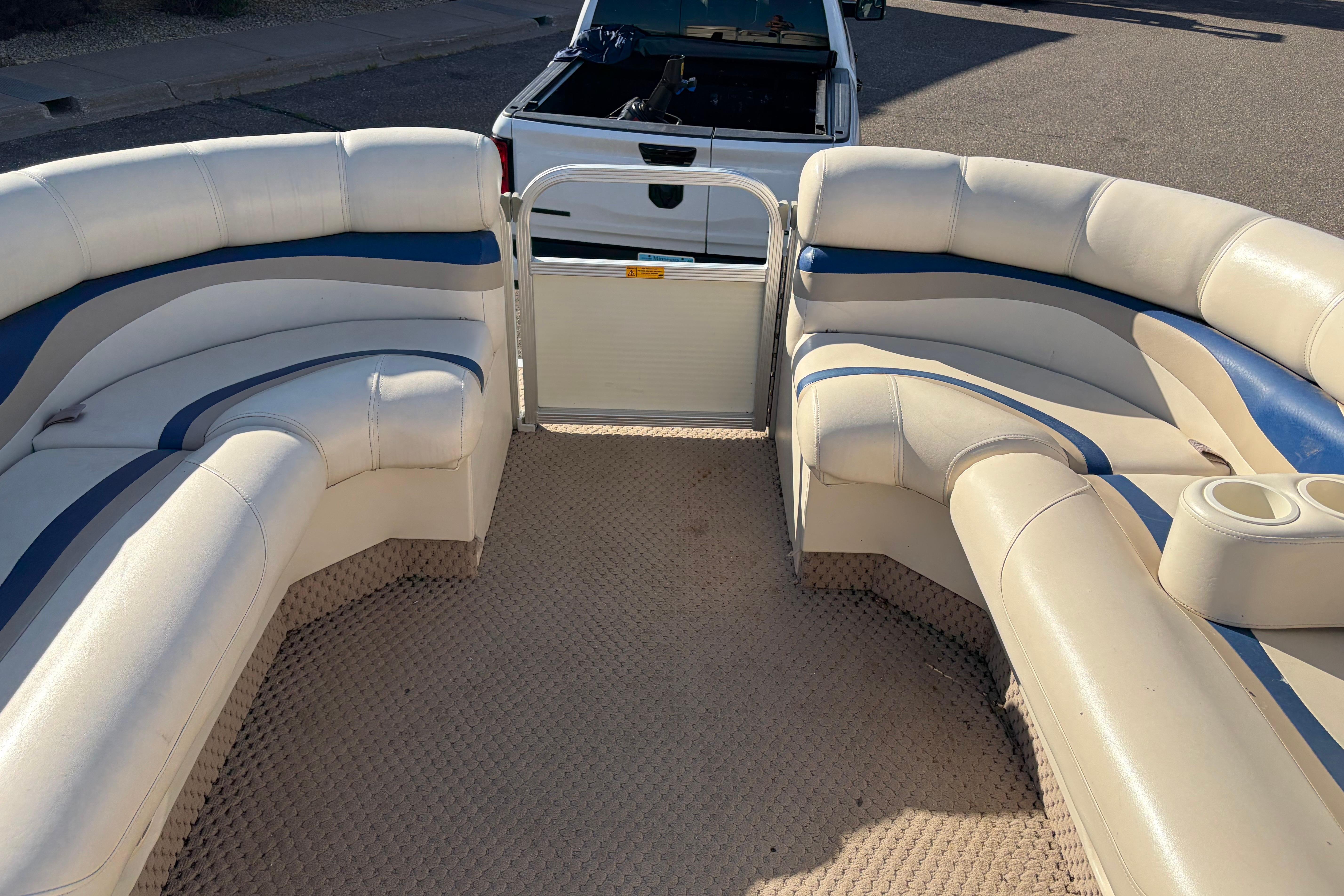 2003 Bennington 2250RSi pontoon boat interior with beige and blue seating, parked near a truck.