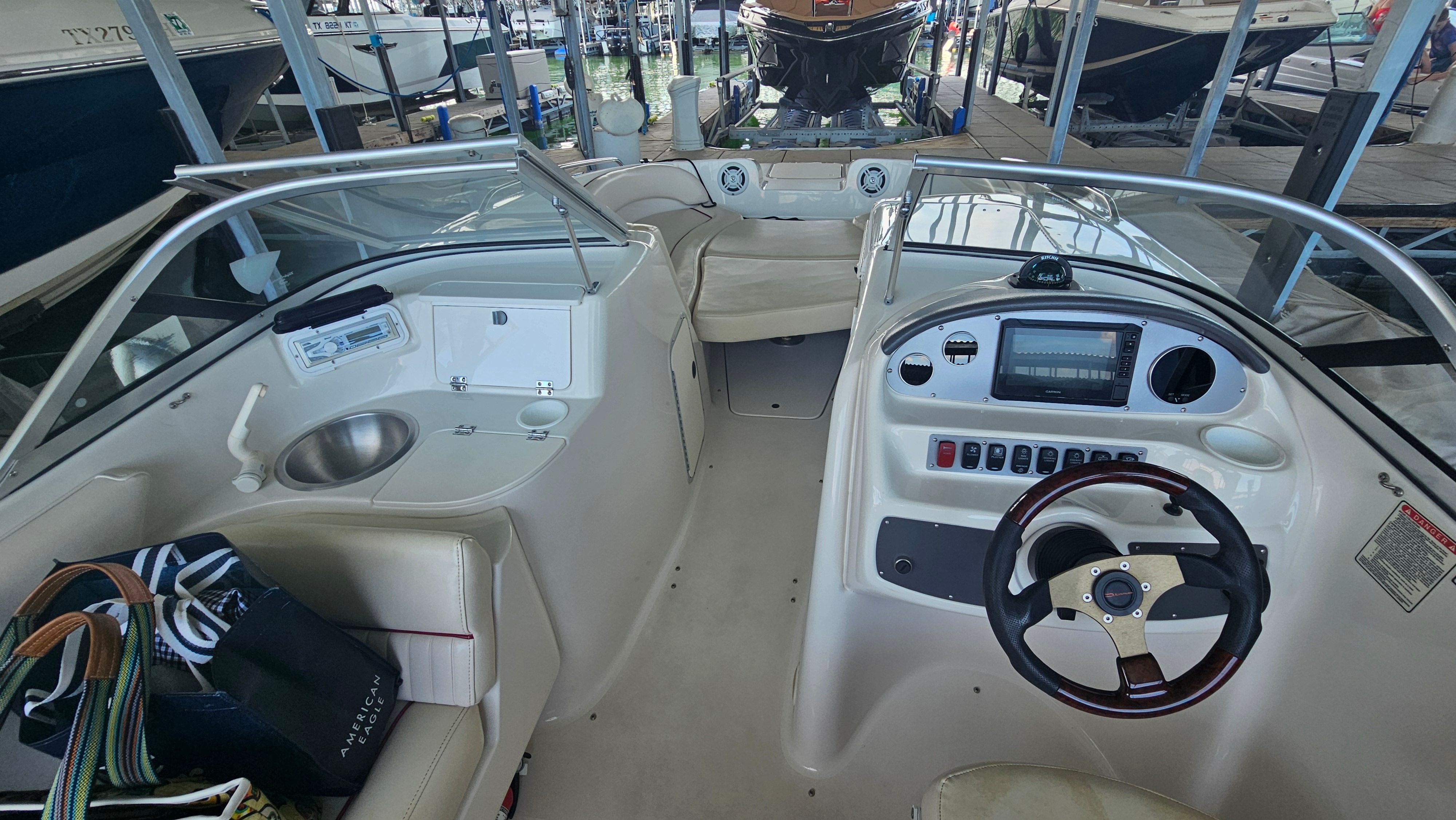 The image shows the cockpit of a 2002 Monterey 220 Explorer Sport boat in a marina.