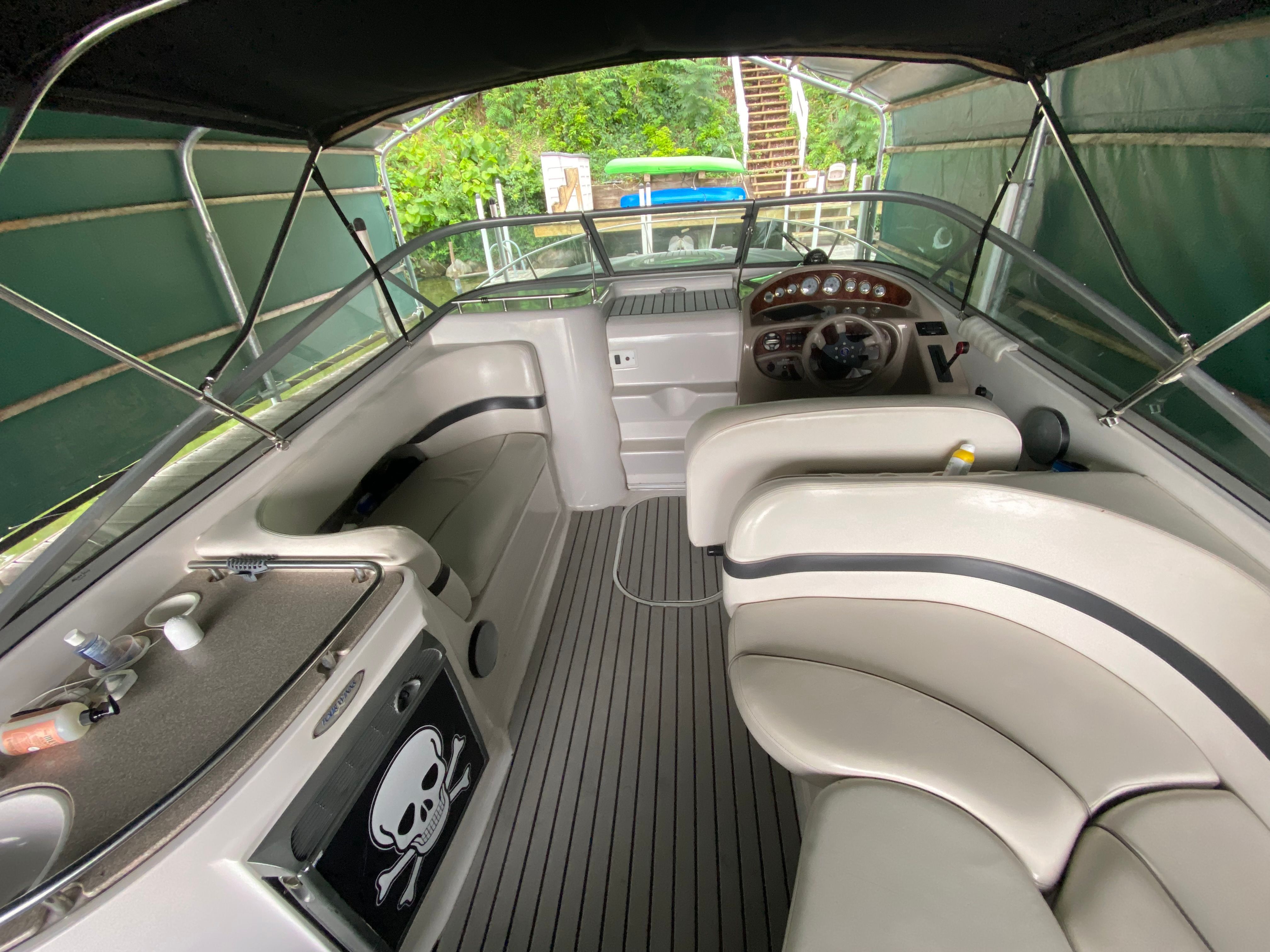 The image shows the cockpit of a 2002 Four Winns 285 Sundowner with cream-colored seating.