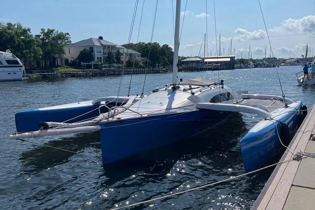 1996 Farrier F-25C trimaran docked in a marina, featuring blue hulls and white deck.