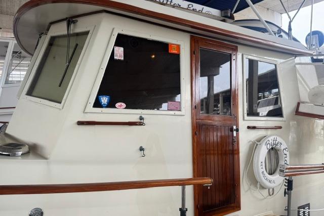1986 Kadey-Krogen 42 yacht with wooden door and life preserver, docked in a marina.