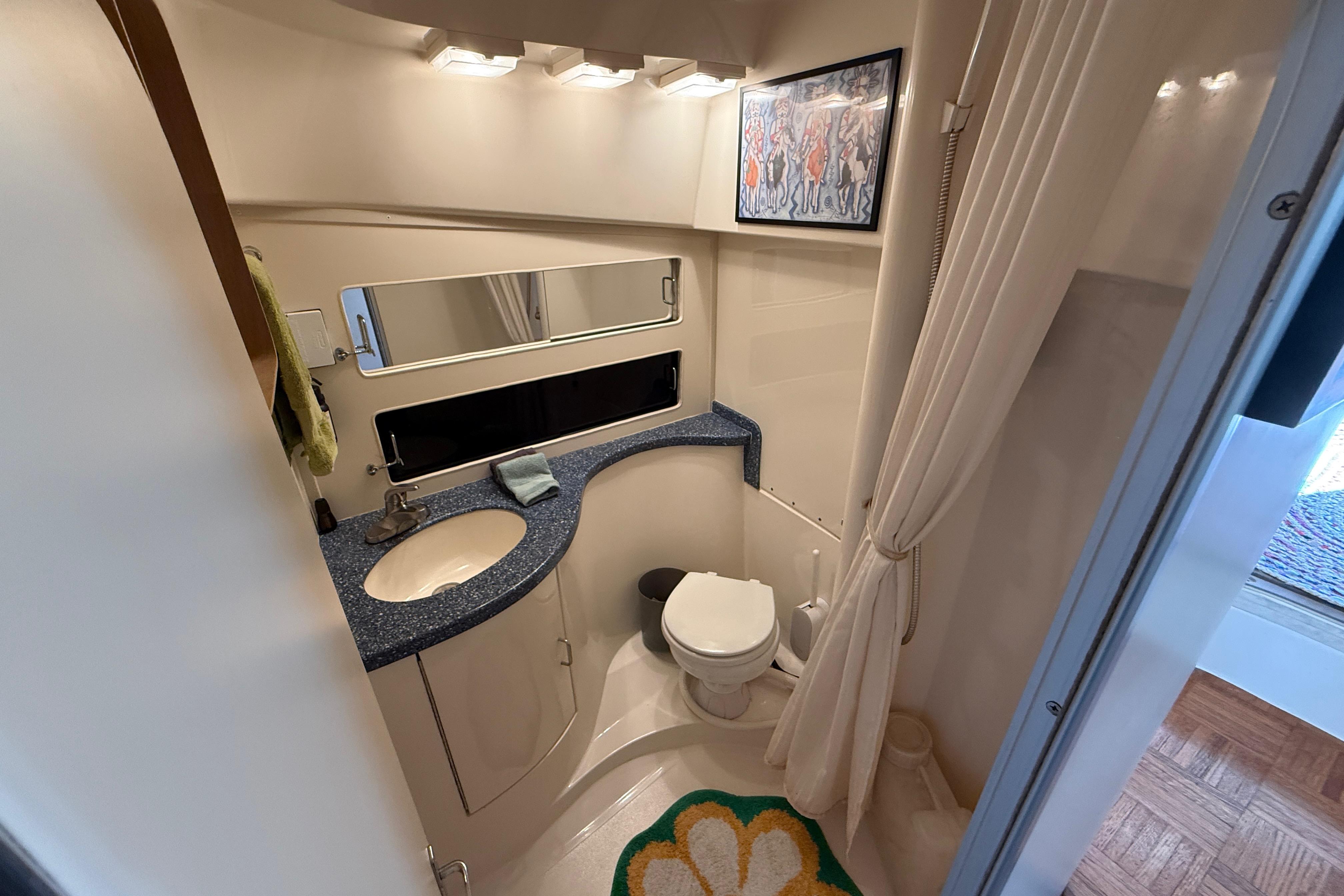 Bathroom interior of 1998 Luhrs Tournament 320 Convertible yacht, featuring sink, toilet, and mirror.