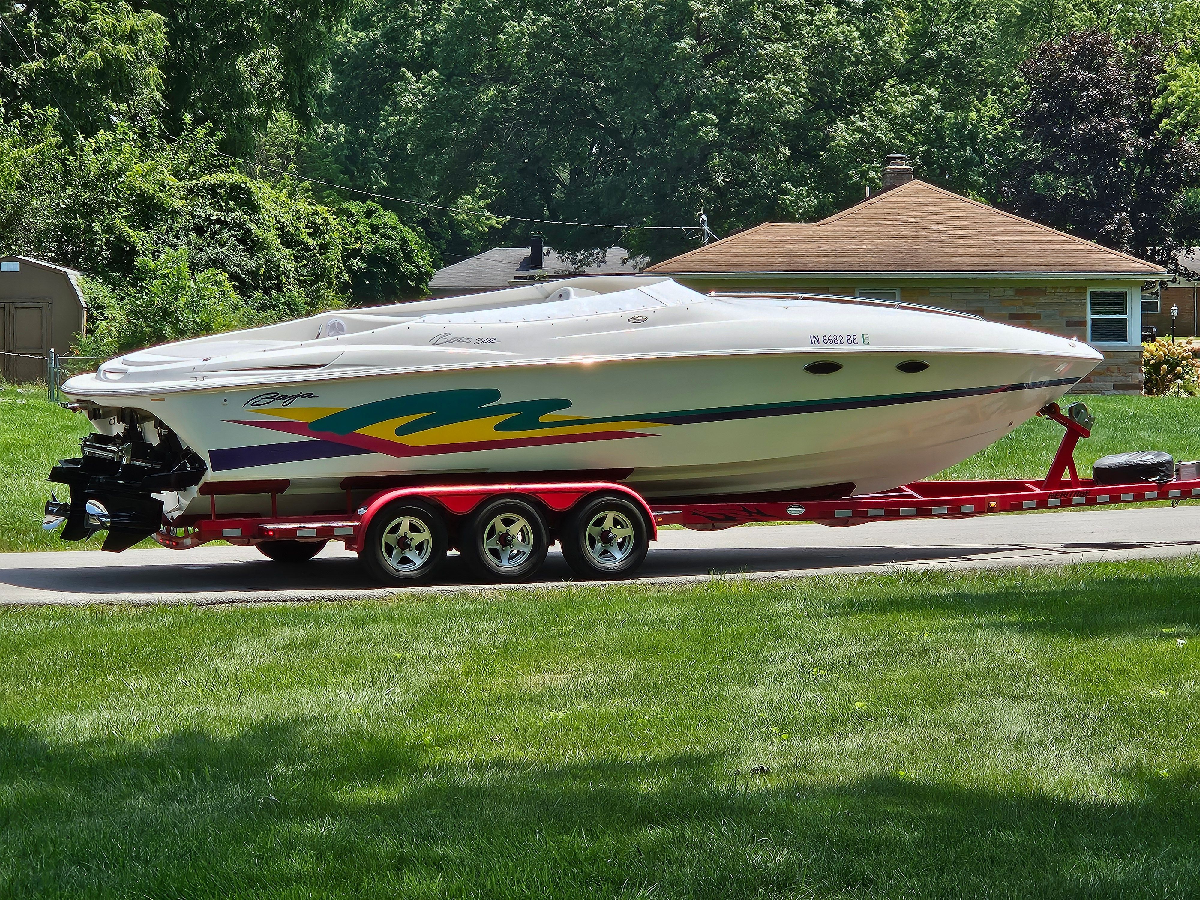 A 1996 Baja 302 Boss on a red trailer, parked on a street in front of a house.