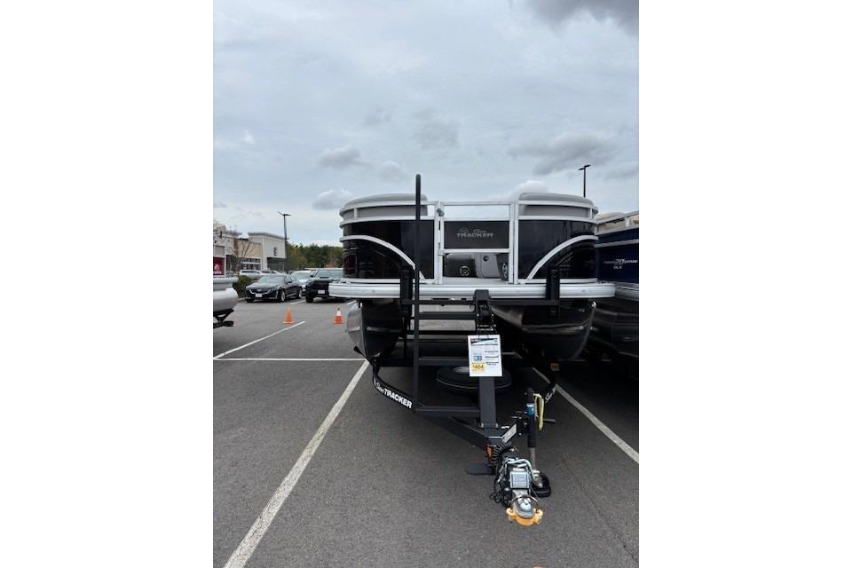 2026 Sun Tracker SportFish 22 DLX pontoon boat on trailer in parking lot.