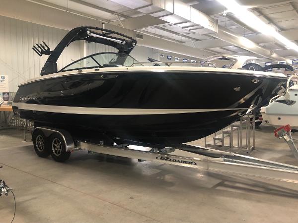 2024 Chaparral 28 Surf boat on trailer in showroom.