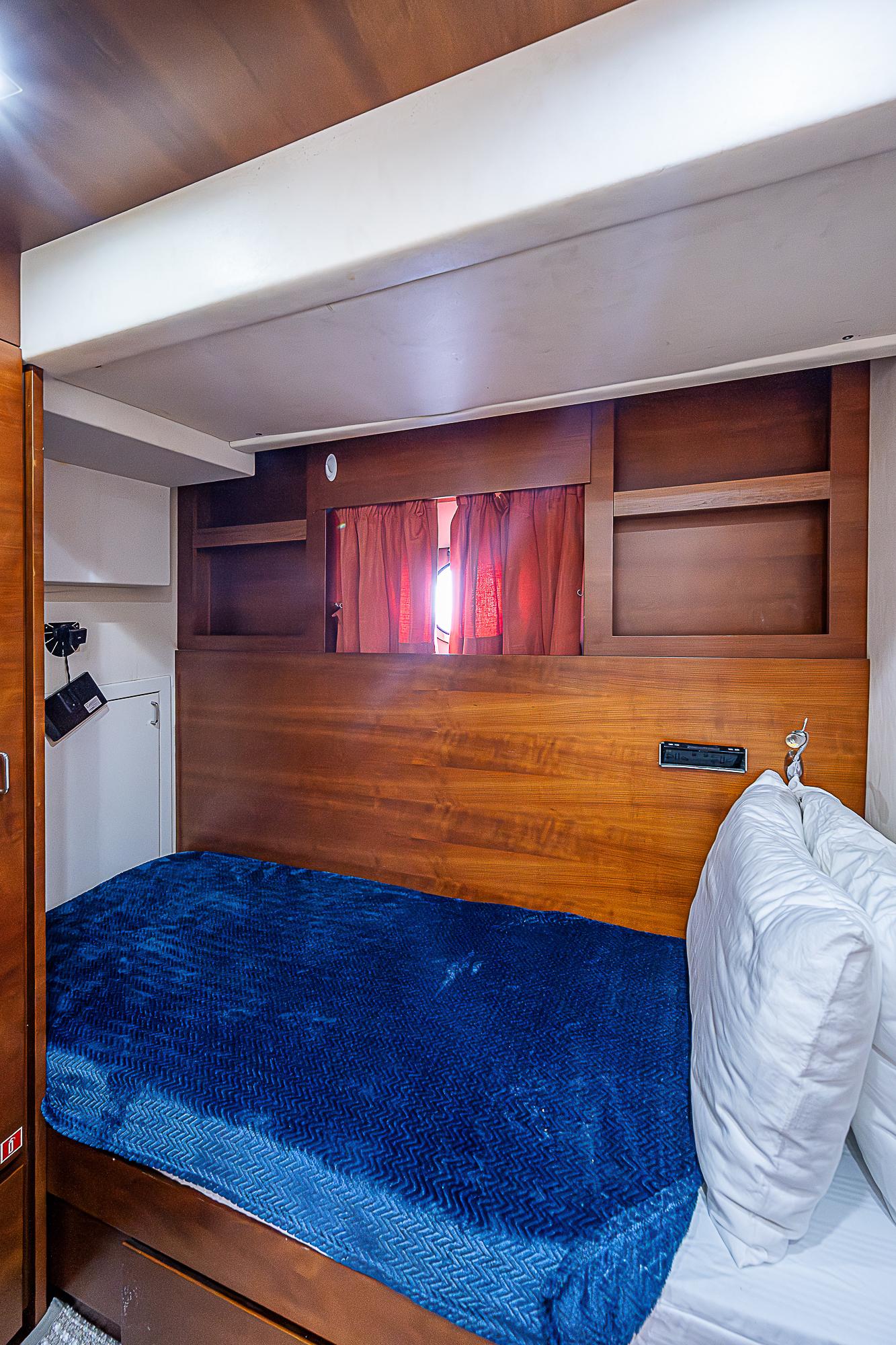Cozy cabin interior of 2011 Azimut 82 yacht with blue bedding and wooden accents.