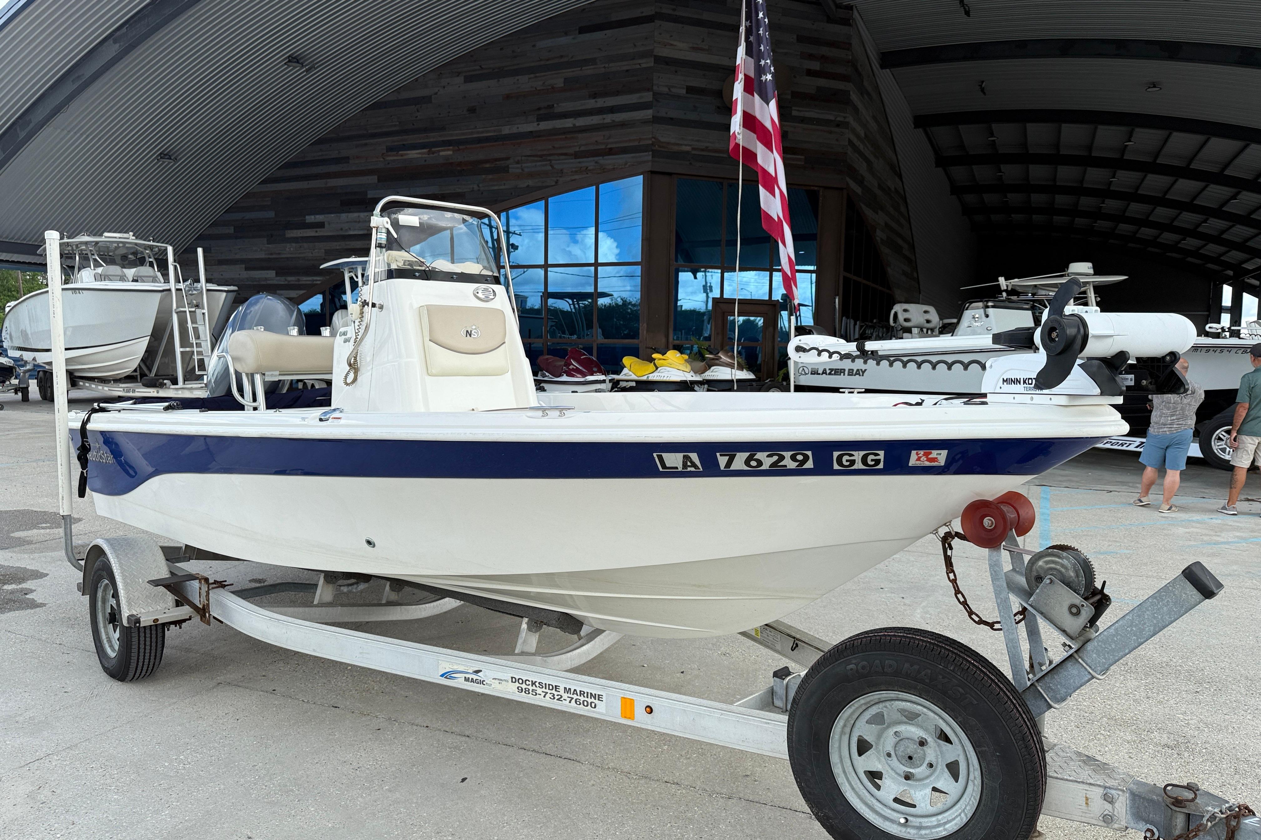 2017 NauticStar 1910 NauticBay boat on trailer, displayed outdoors with American flag.