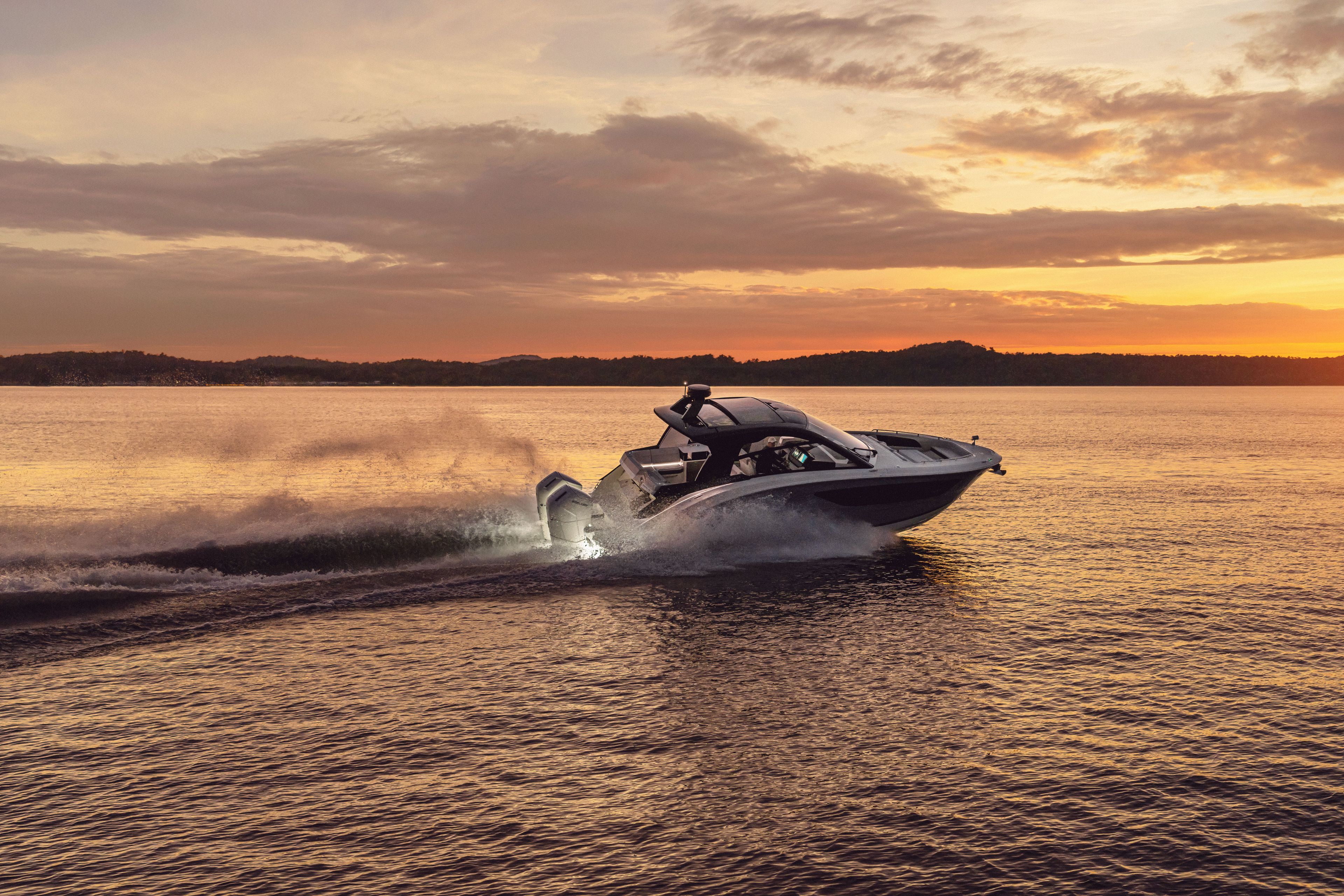 A Sea Ray Sundancer 370 Outboard cruising on the water at sunset.
