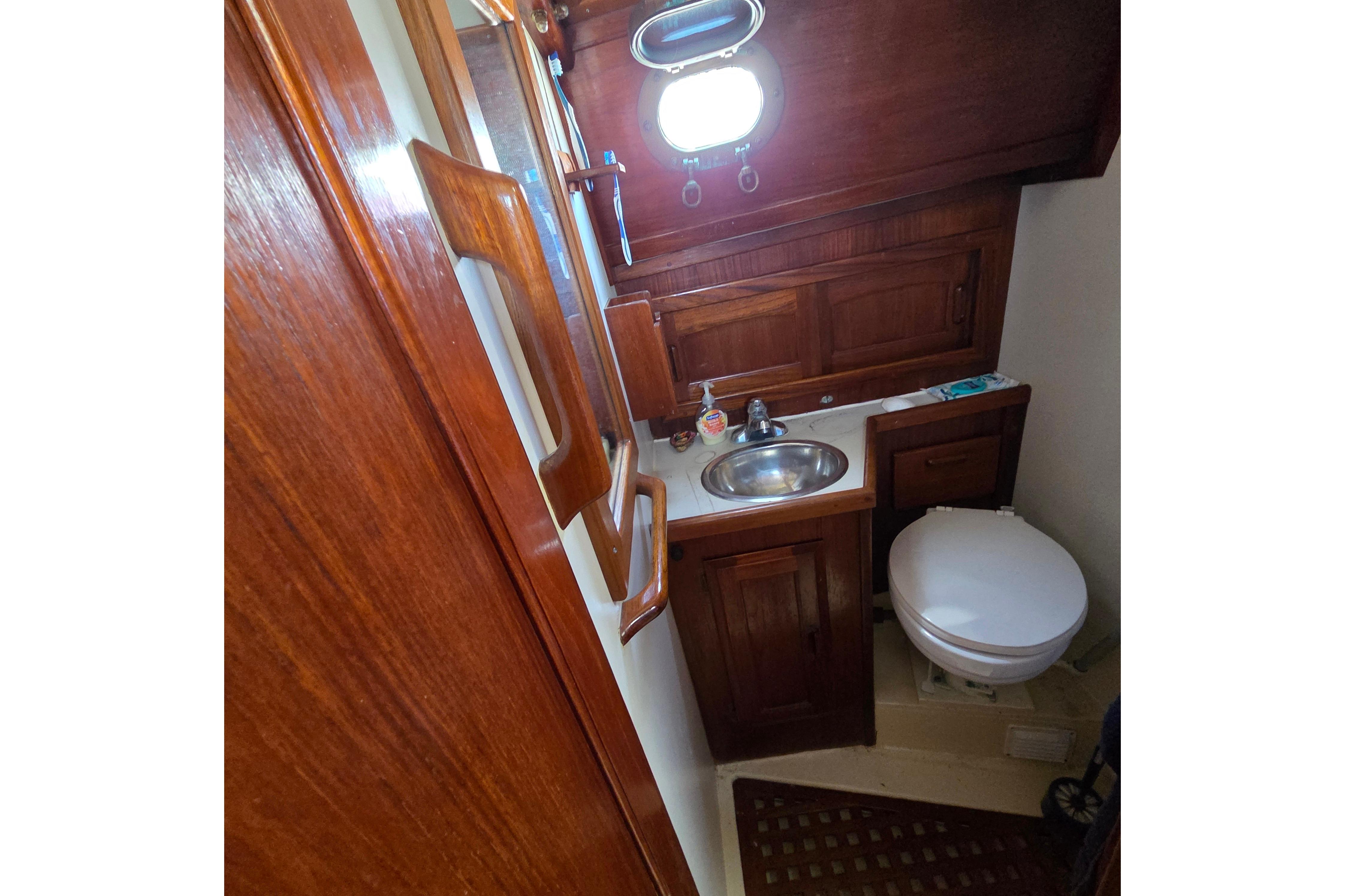 1983 Pacific Seacraft 34 yacht bathroom with wooden cabinetry and stainless steel sink.