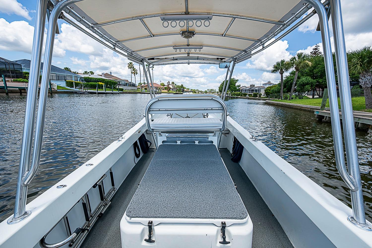 Custom 1969 boat interior with canopy, cruising on a scenic waterway under a blue sky.