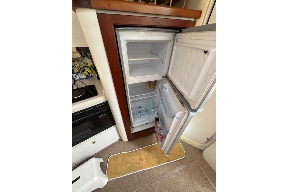Open refrigerator inside 1999 Cruisers 3870 Express yacht, showcasing interior storage space.