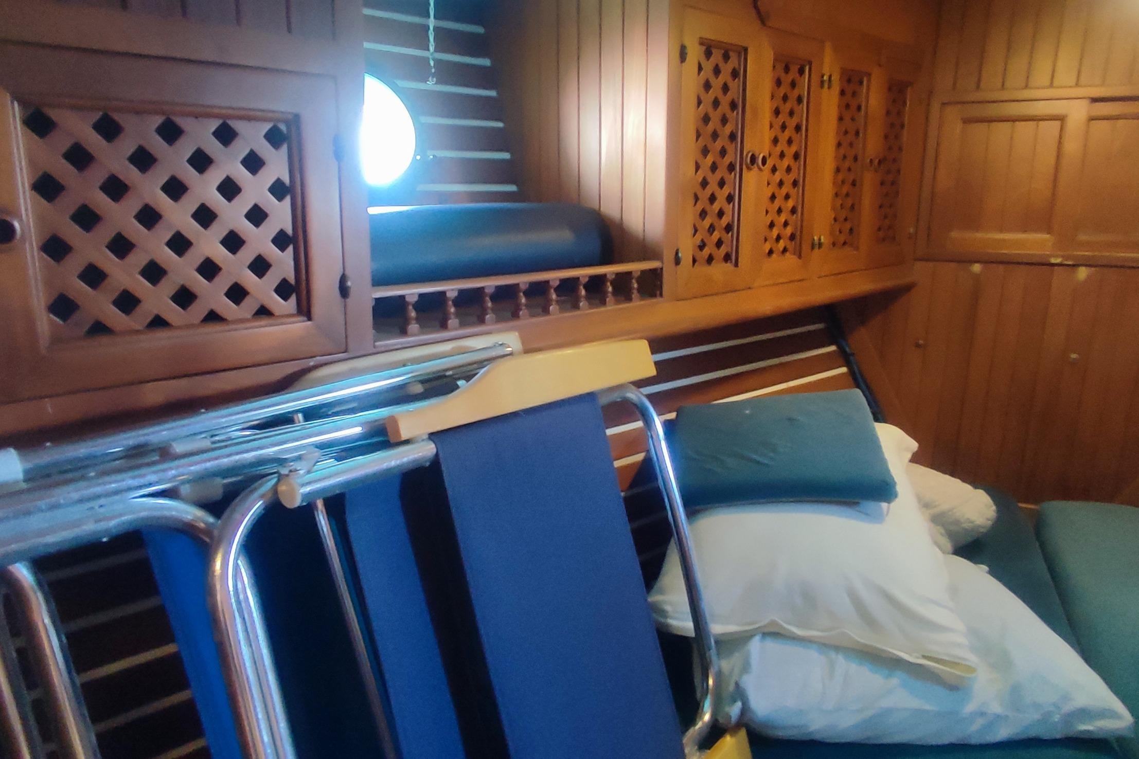 Cozy cabin interior of a 1980 Formosa 51 yacht with wooden paneling and cushions.