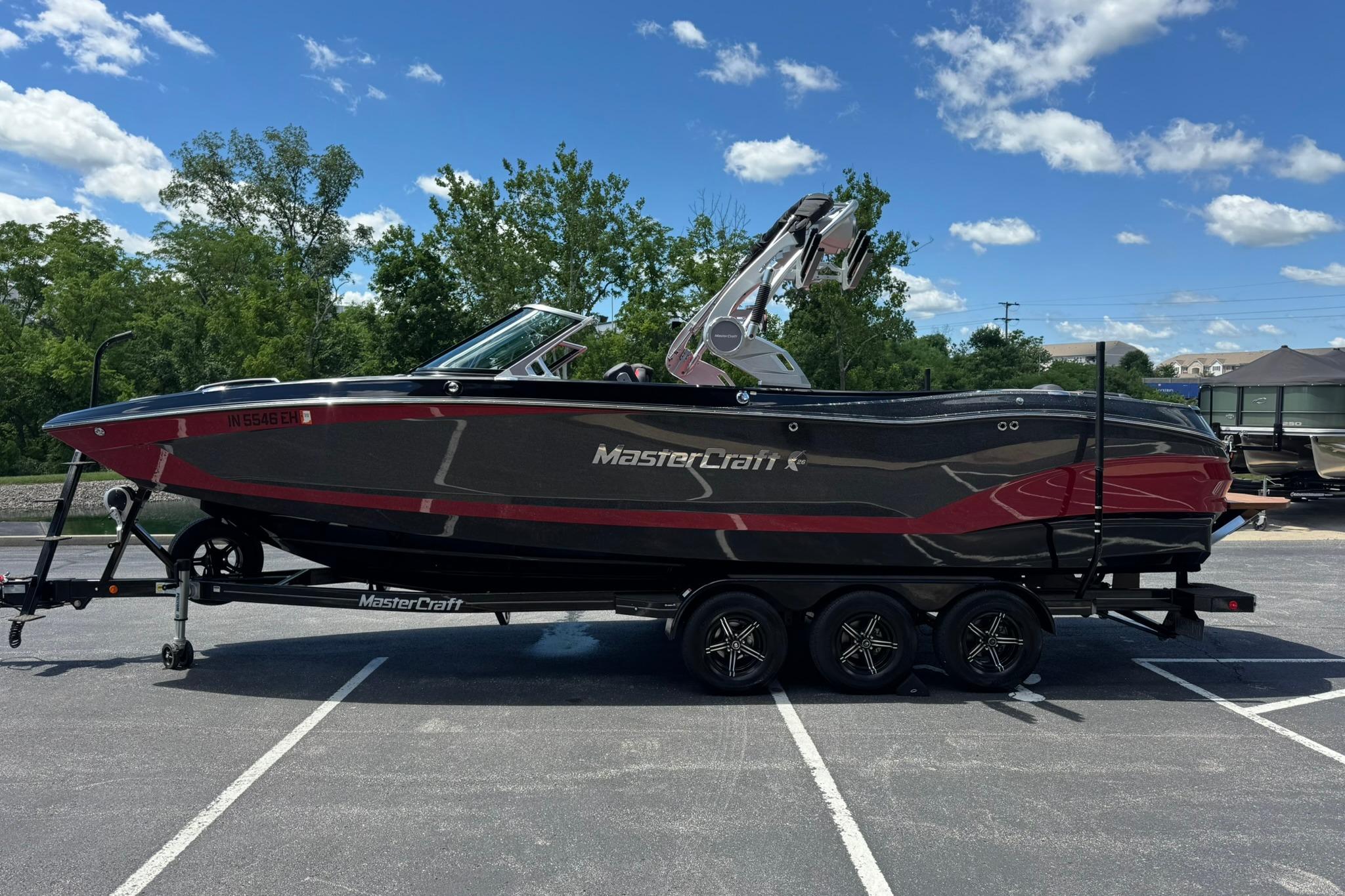 2021 MasterCraft X26 boat on trailer, parked in a lot under a clear blue sky.