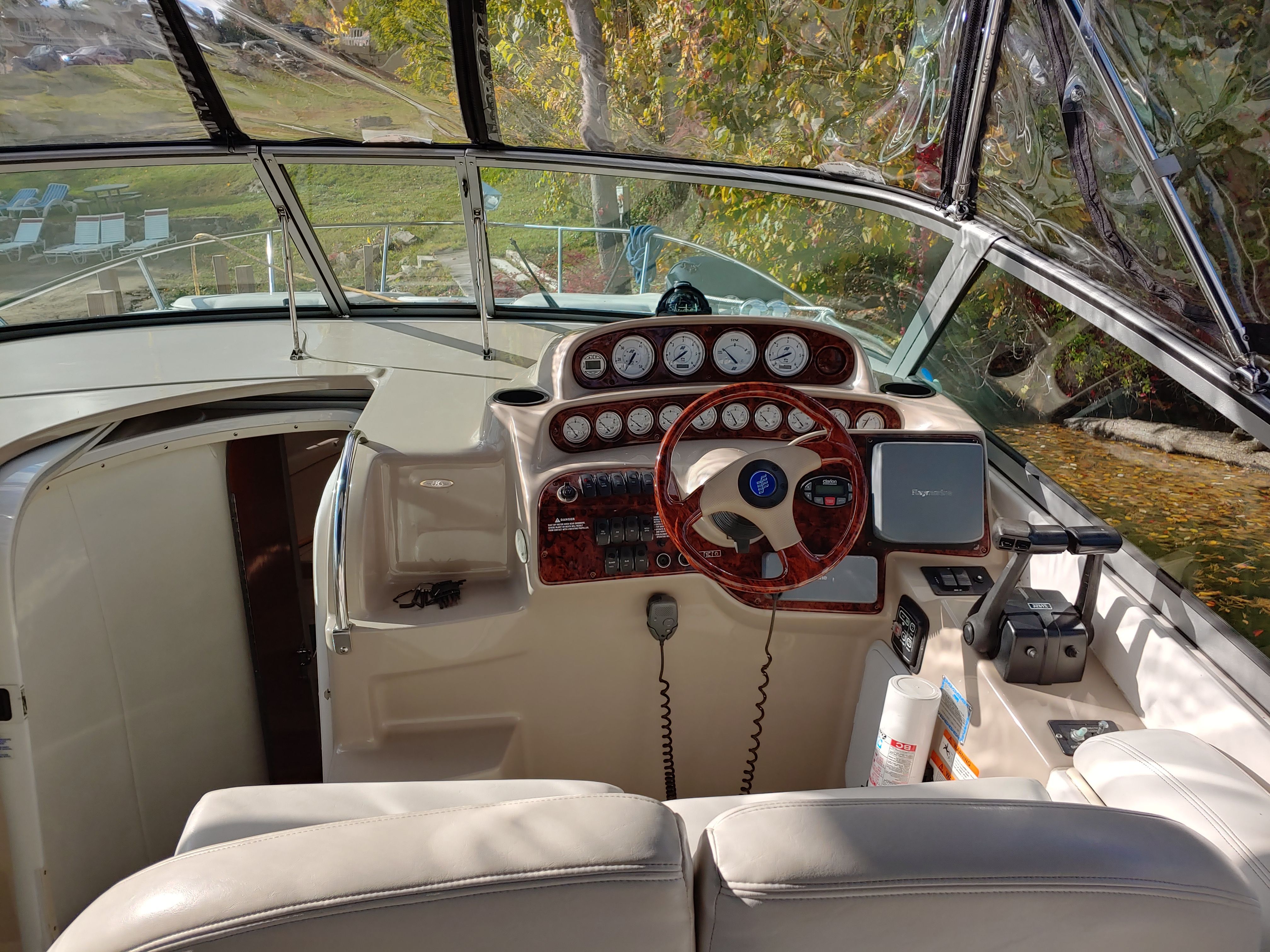 The cockpit of a boat with a wooden steering wheel and multiple instrument gauges.