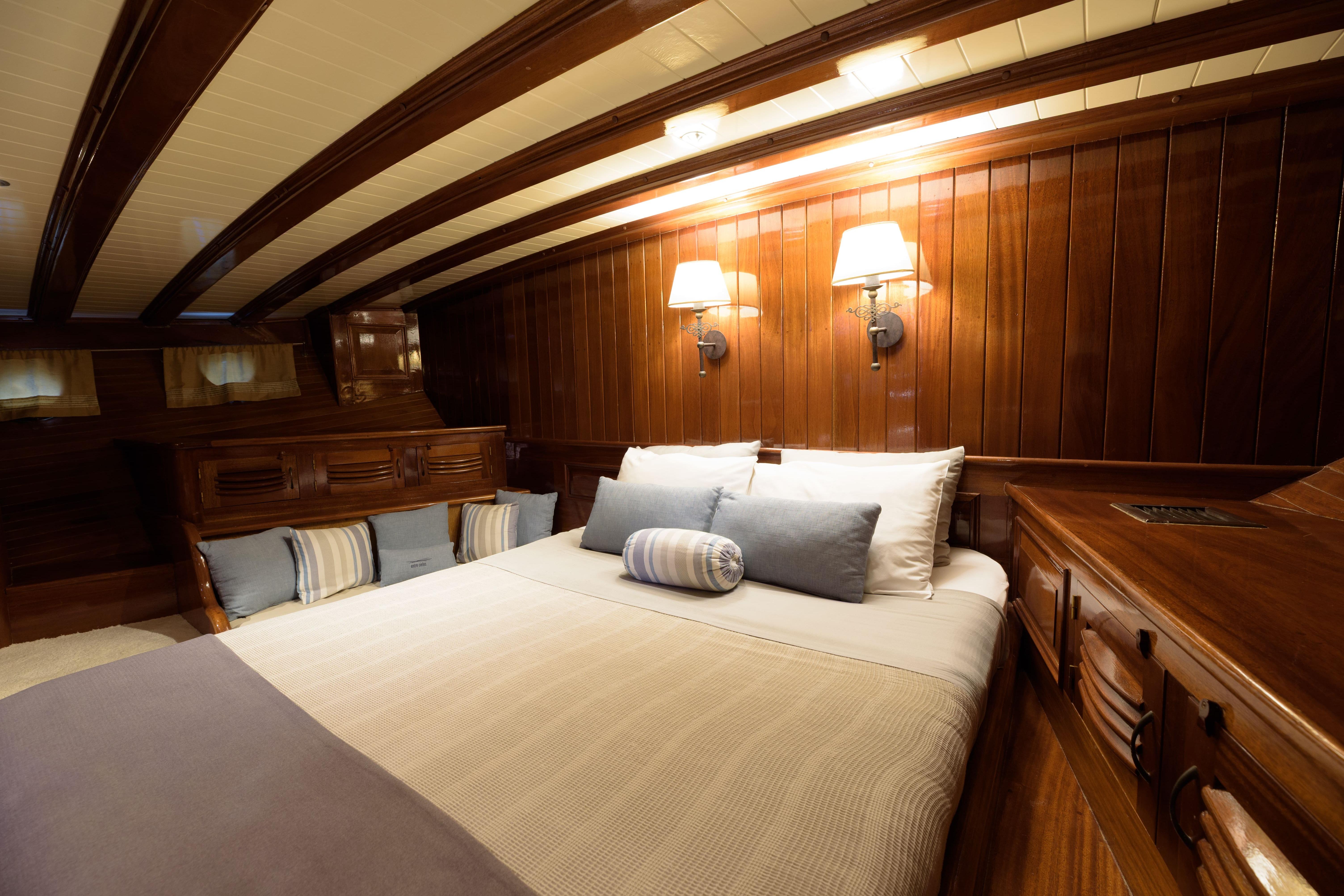 Luxurious wooden cabin interior of 2004 Su Marine Gulet with cozy bedding and ambient lighting.
