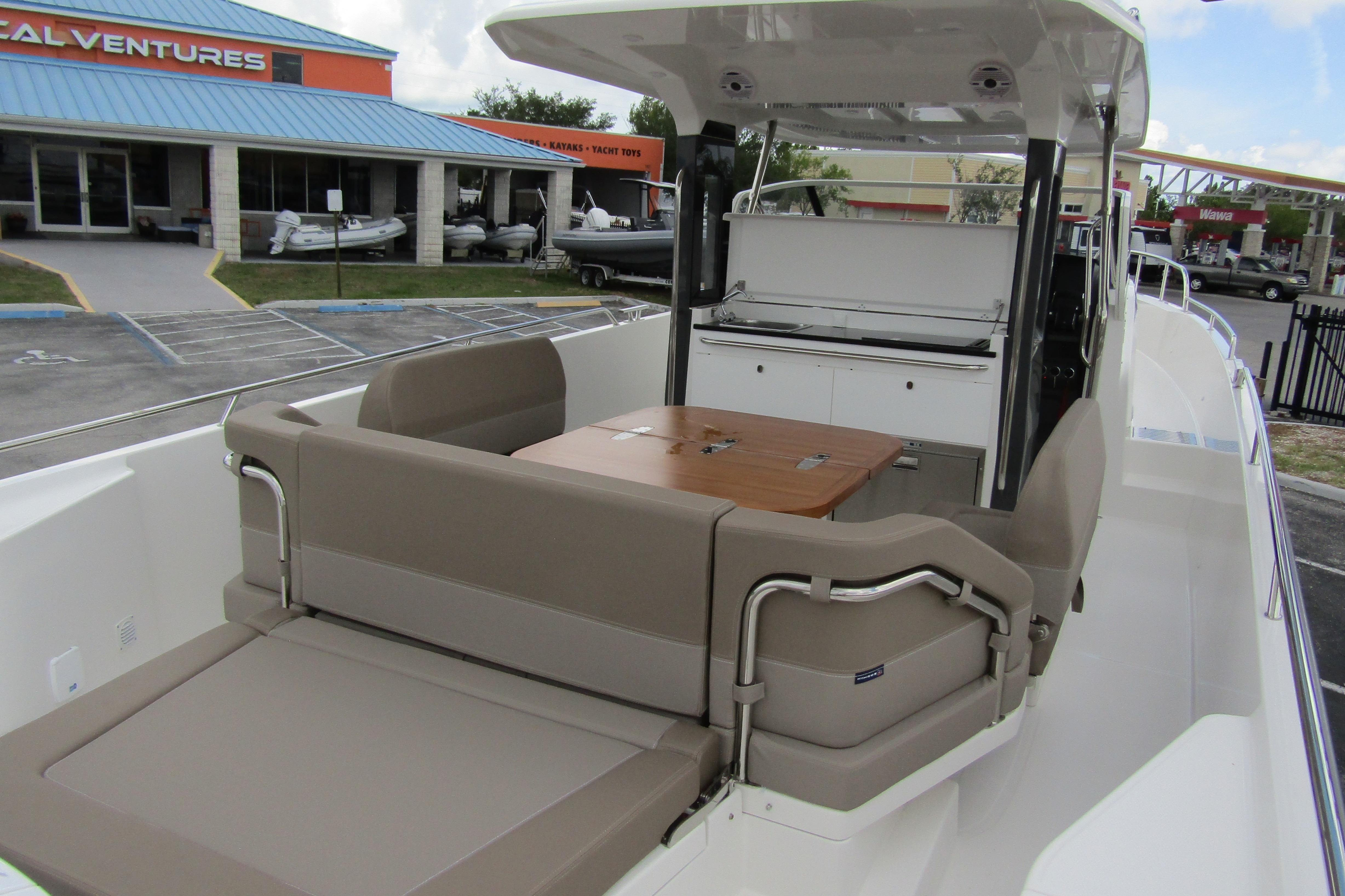 2025 Nimbus Tender 11 boat interior with seating and table, docked near a marine store.