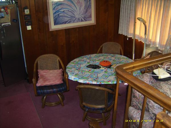 Cozy dining area on 1980 Pluckebaum Baymaster with round table, chairs, and wall art.