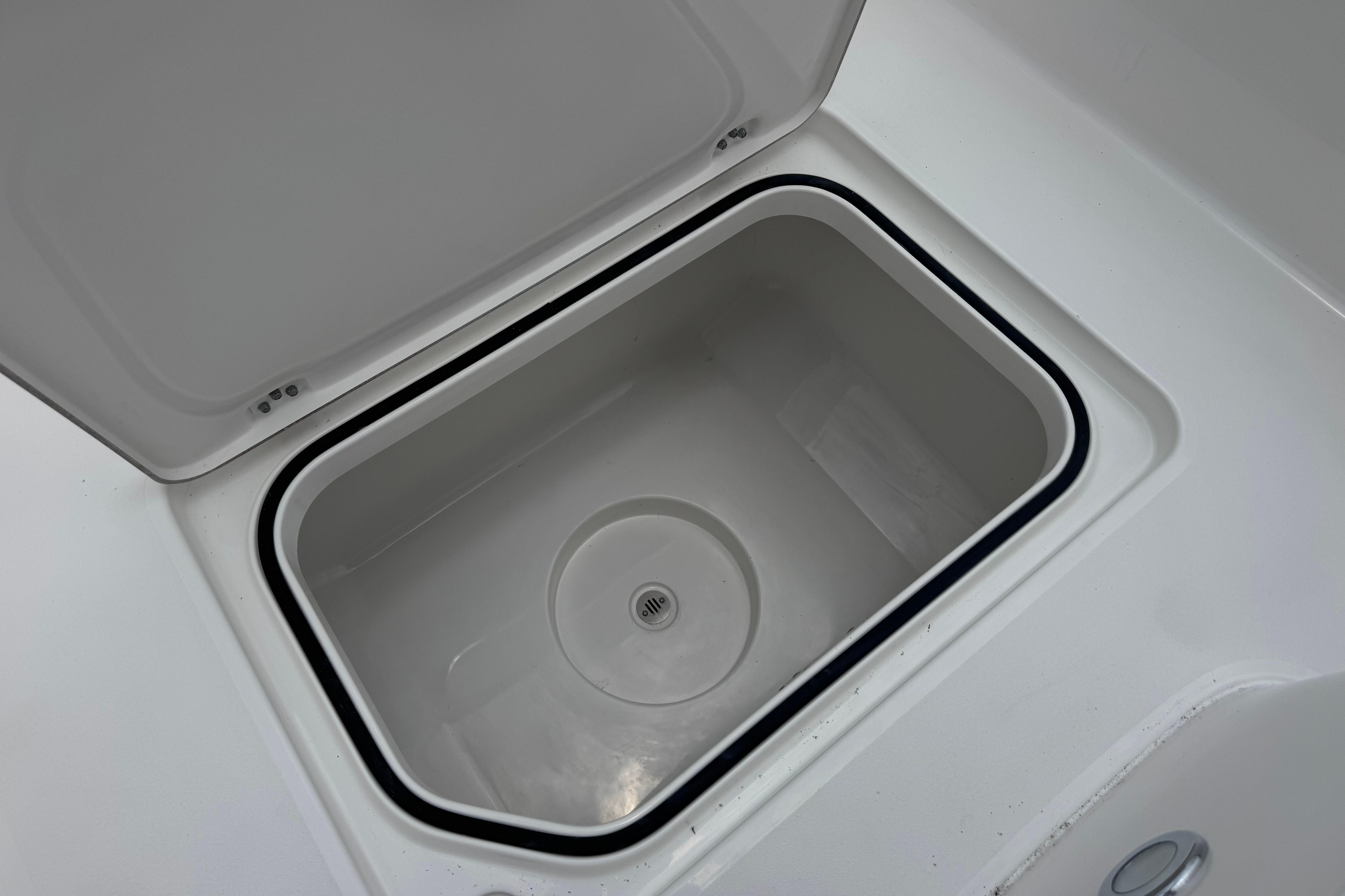 Open storage compartment on 2027 Caymas 26 HB boat, featuring a sleek white interior.