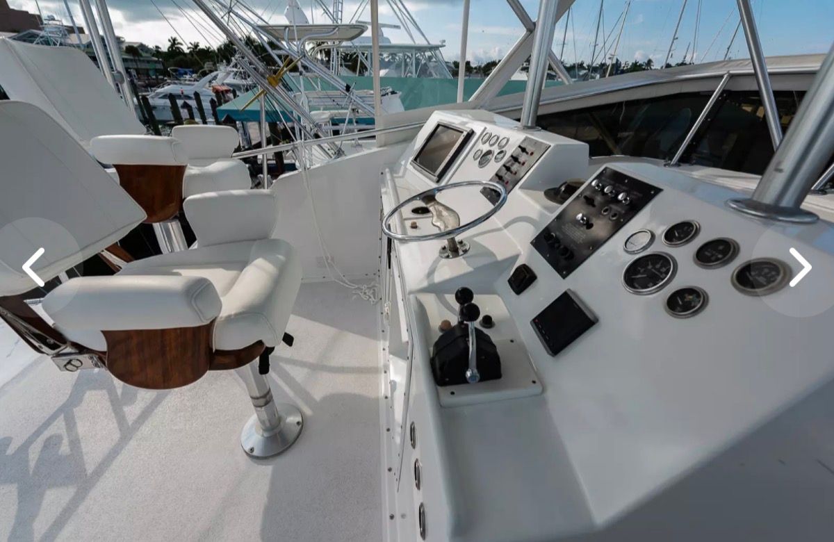 The image shows the helm of a 1979 Hatteras sport fishing yacht with white seats and instruments.