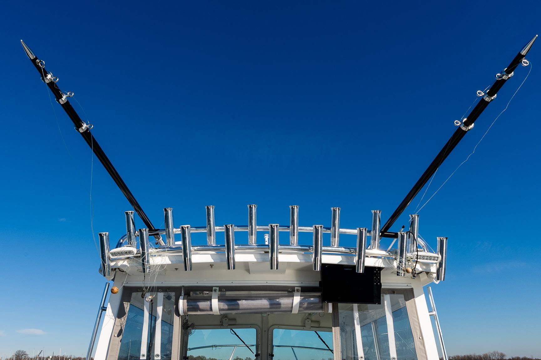 2024 Steiger Craft 31 Fisherman boat with fishing rod holders against clear blue sky.
