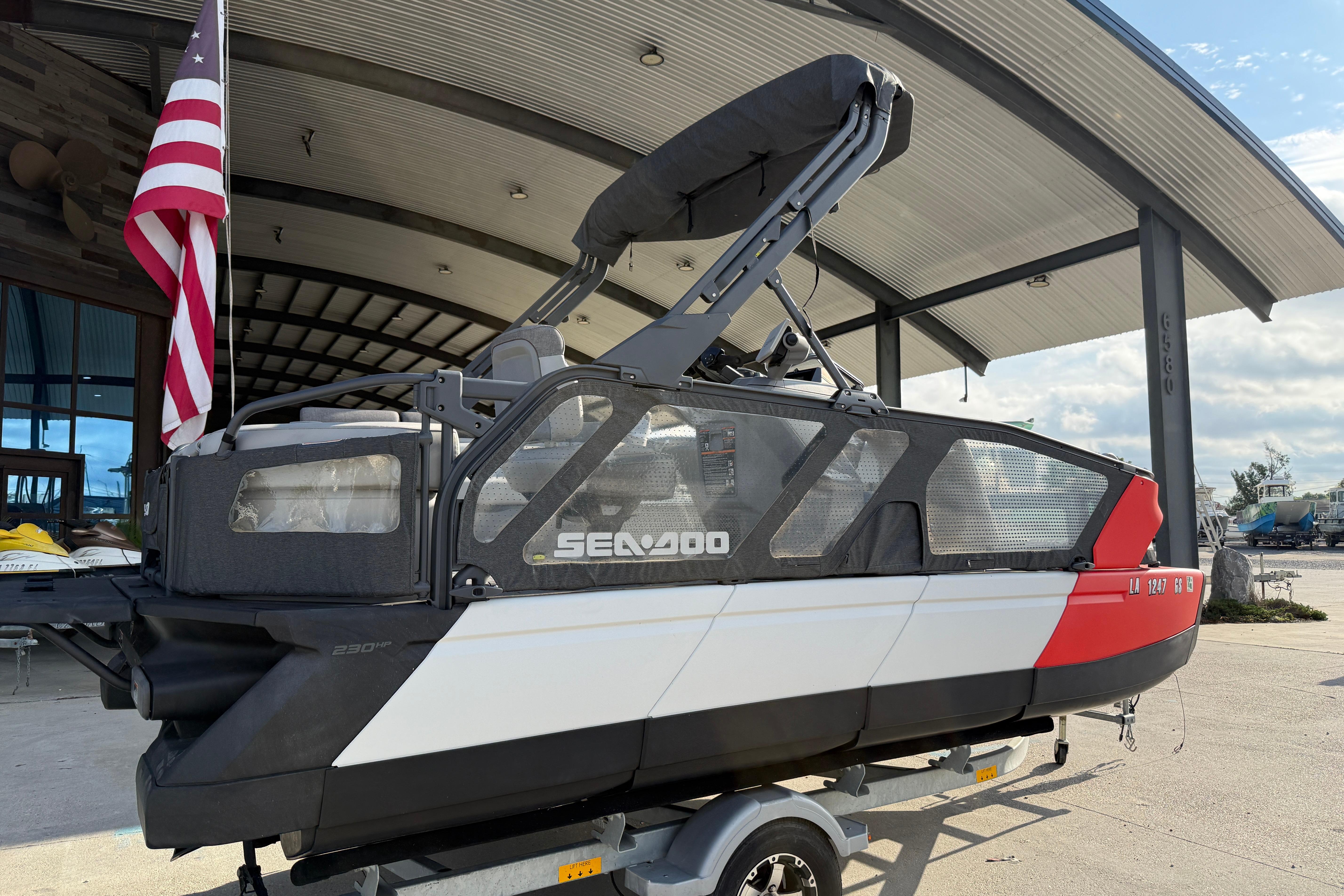 2023 Sea-Doo Switch Sport 18 pontoon boat with American flag, docked under a canopy.