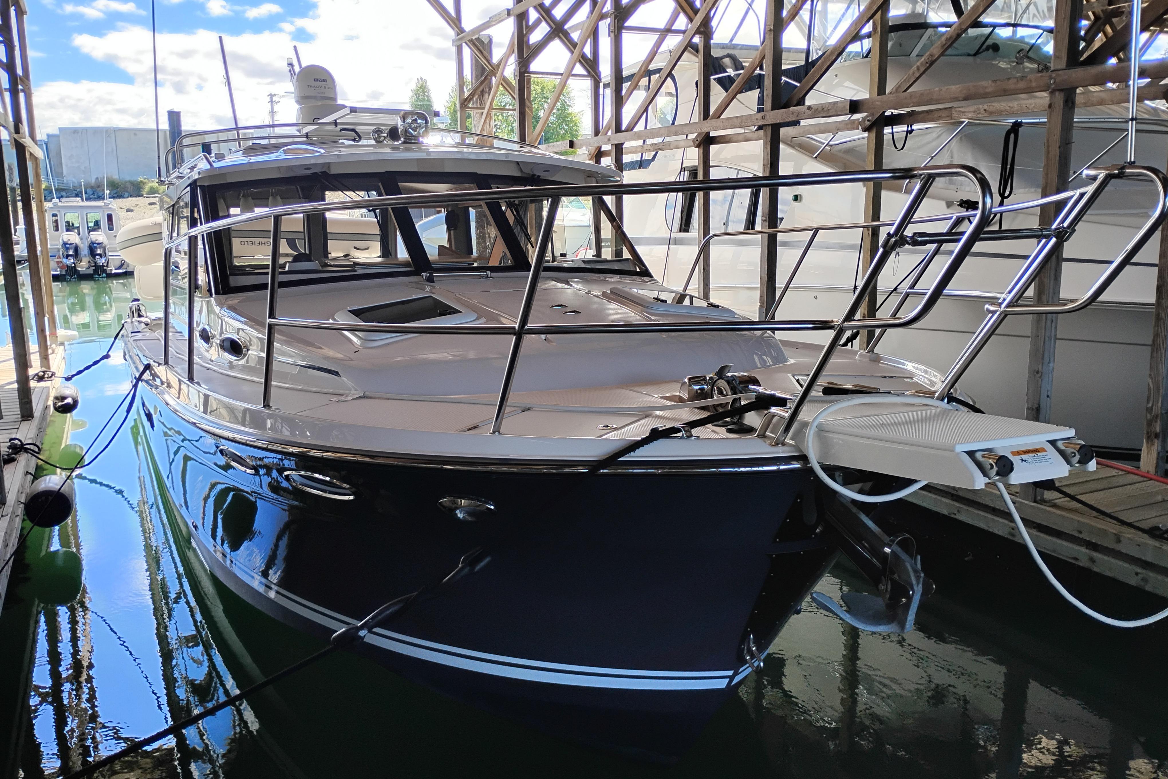 2022 Cutwater C-32 Coupe docked in a marina under a wooden shelter.